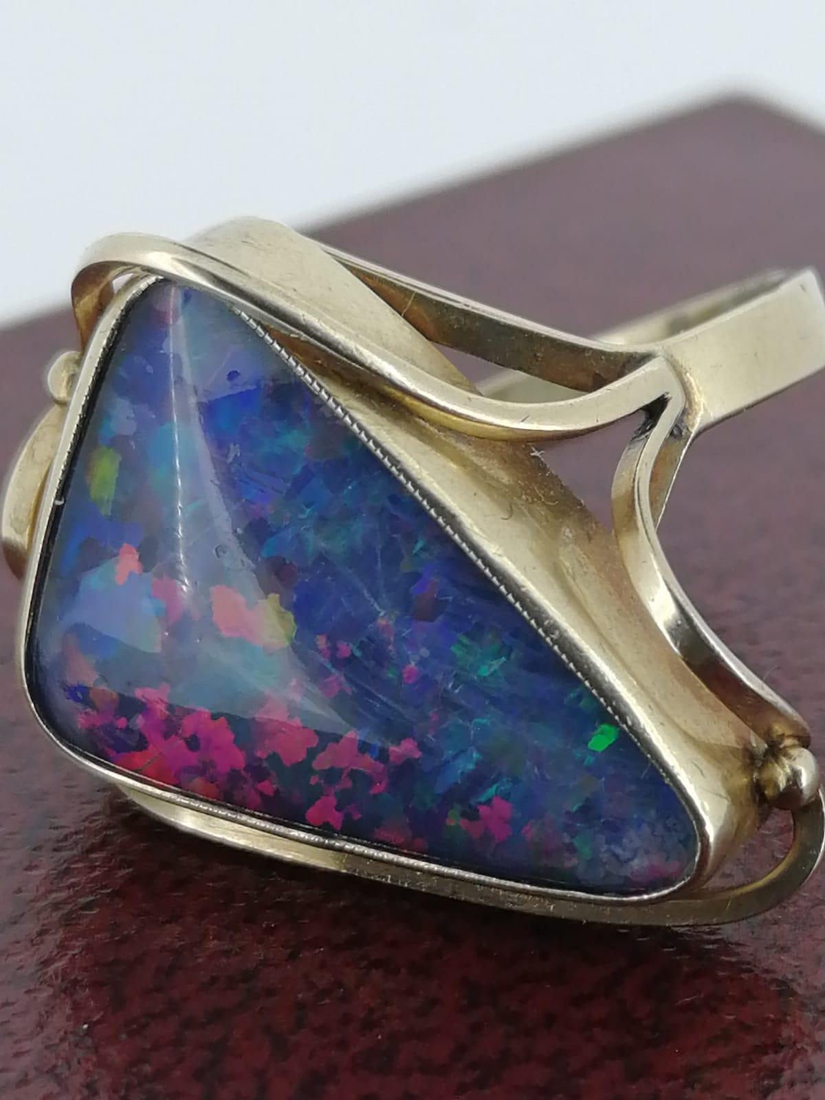 Of Australian provenance, 
this ring is crafted in 9K Yellow Gold,
centrally set with 
an Australian Opal Doublet 
of very unusual triangle shape
of impressive 4.50ct 
(20mm x 14mm approx.), 
displaying the most unique & stunning 
myriad of