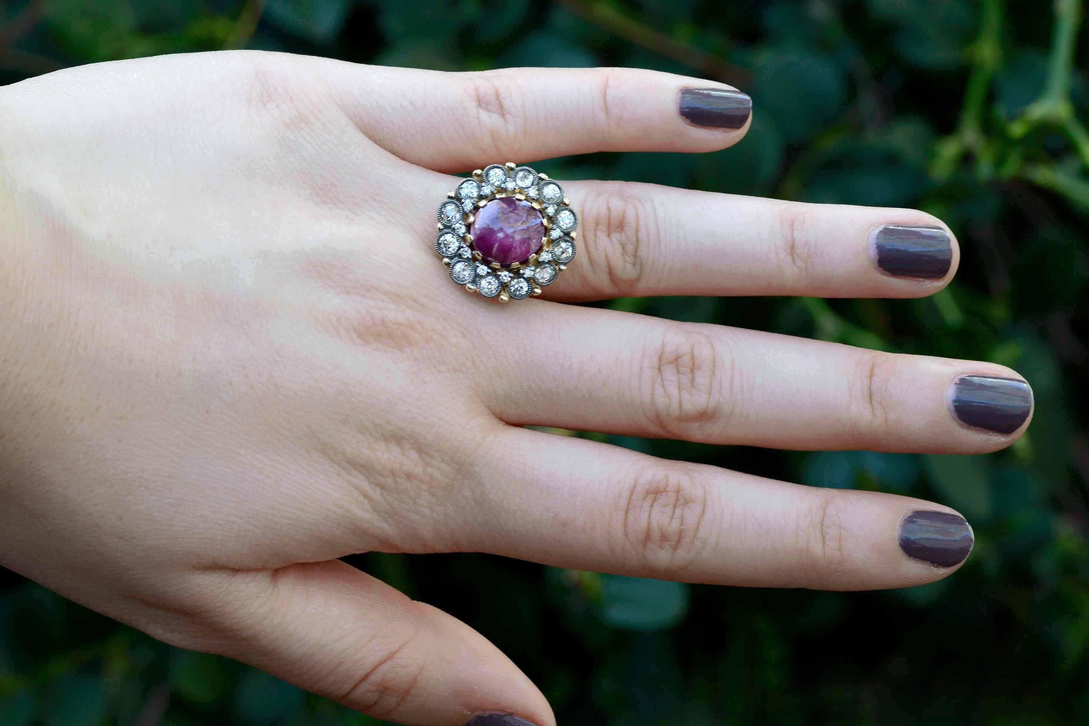 A simply scrumptious rare star ruby sits proudly at the center of this alluring statement ring. Surrounded by an inner circle of round sparking diamonds and framed by 12 chunky, old mine cut round diamonds each set within a millegrain bezel of white