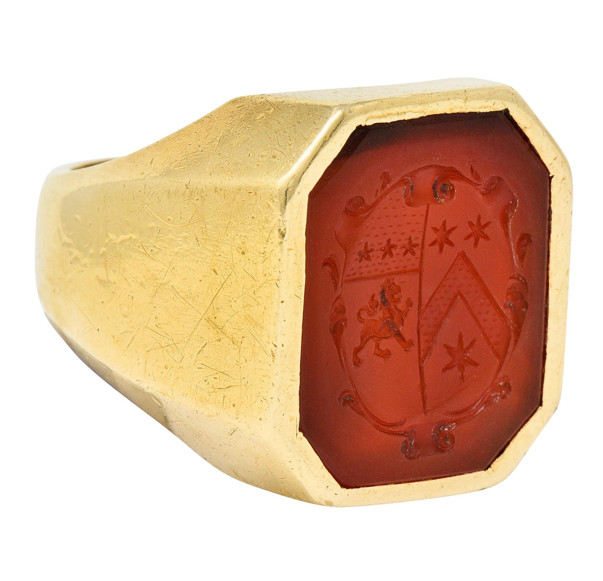Hexagonal mounting centers a bezel set tablet of translucent orangey-red carnelian

Deeply engraved to depict a shield emblazoned with stripes, stars, and a fierce but stylized lion

Carnelian measures approximately 18.4 x 15.5 mm

Stamped 14K for