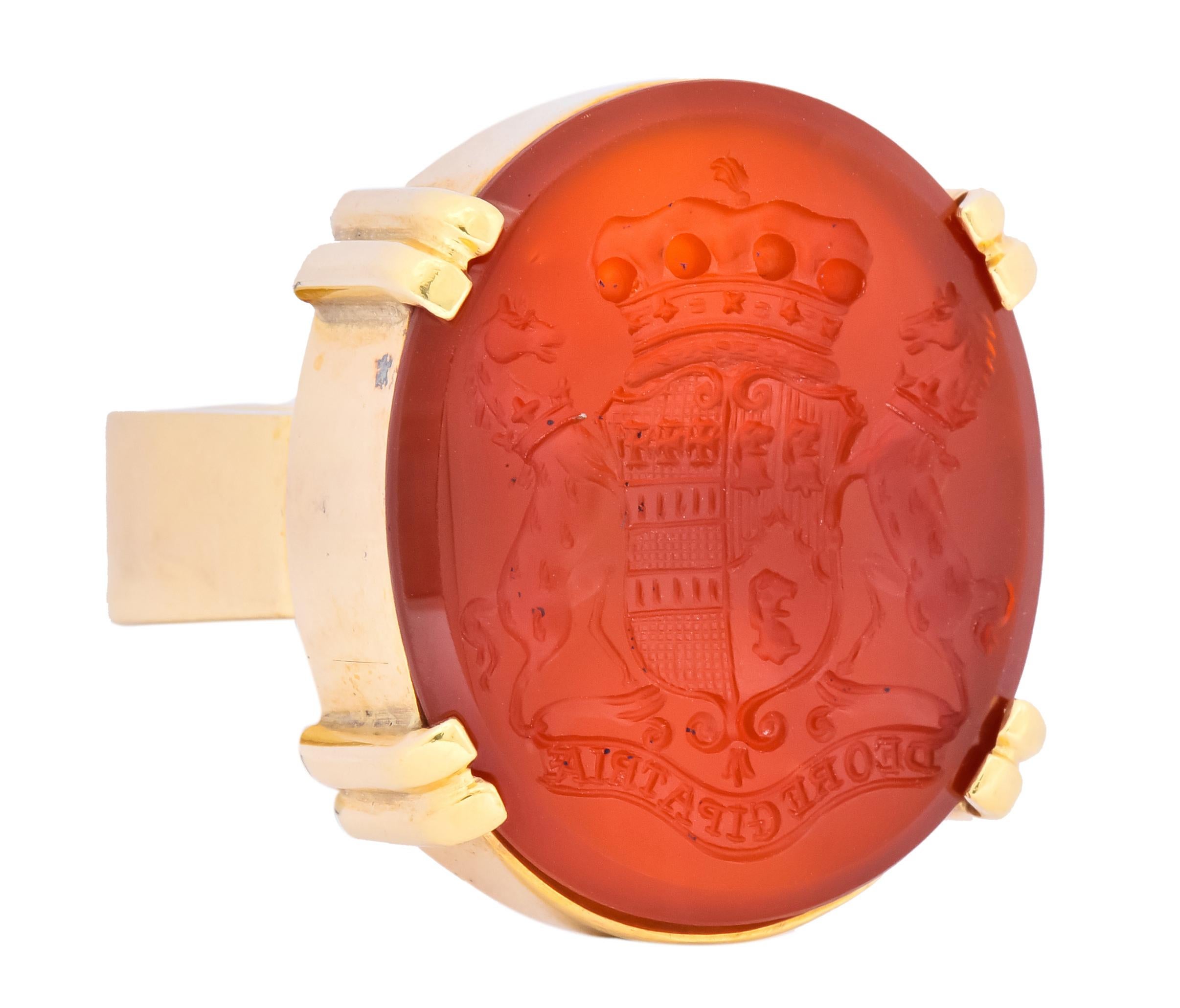 Centering a deep reddish-brown carnelian intaglio, double prong set 

Intaglio depicts a crest flanked by rearing stallions with inscription “Deo Regi Patria”, Latin for “Country is governed by God”

Circa 1950

With maker's mark and stamped 18k for