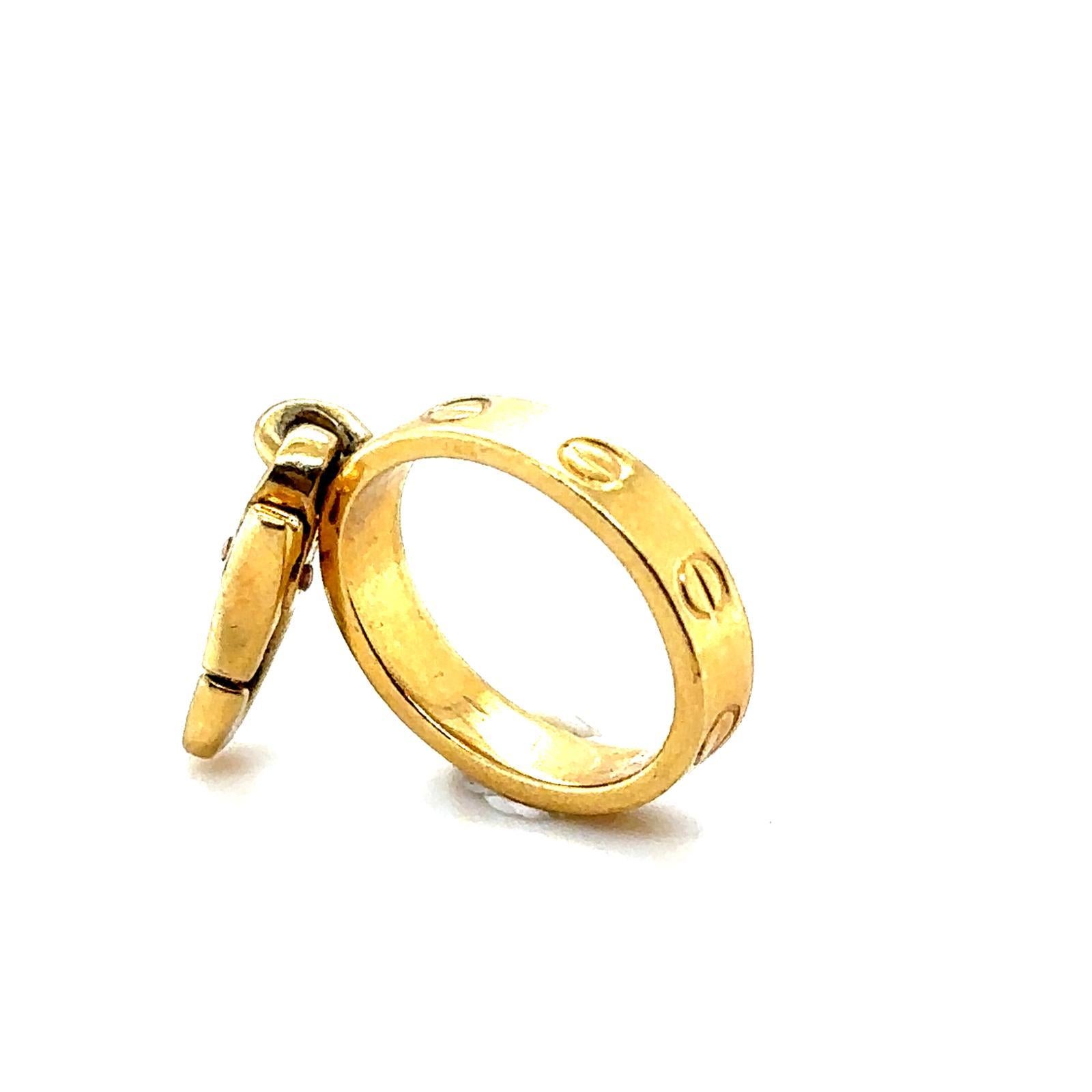 Un bellissimo charm in oro giallo 18 carati di Cartier, creato come versione in miniatura dell'iconico braccialetto Love per la sua collezione di charmal, per arricchire bracciali o collane. 

Qui è mostrato insieme ad altri charme classici di