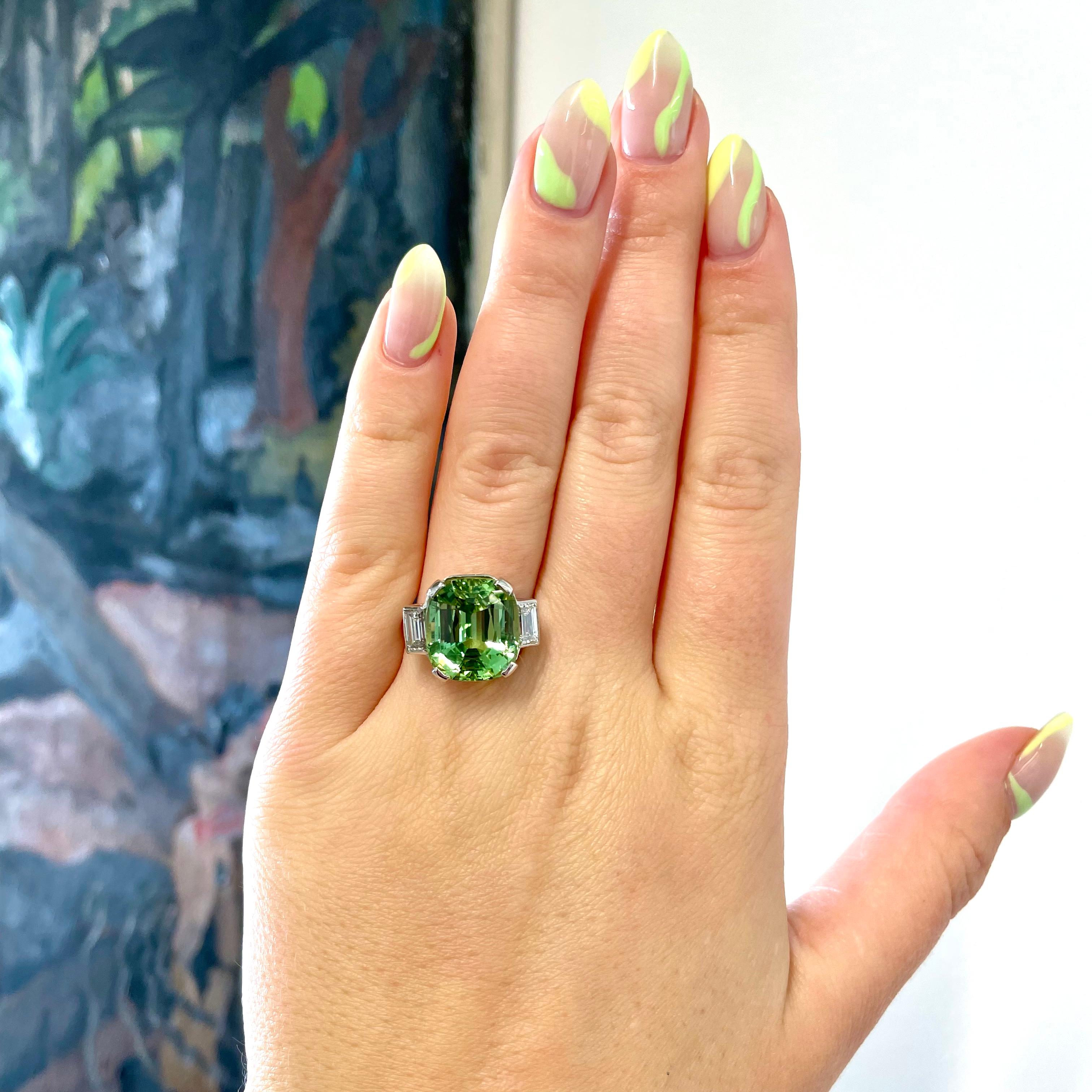 Retro Mint Green Tourmaline Diamond Cocktail Ring. The ring feature a vibrant peridot weighs 11.36 carats. Accented by 2 baguette cut diamonds approximately, 0.80 carat, H-I color, VS clarity. Circa 1950's. Size 5 1/2 and can be resized. 

About The