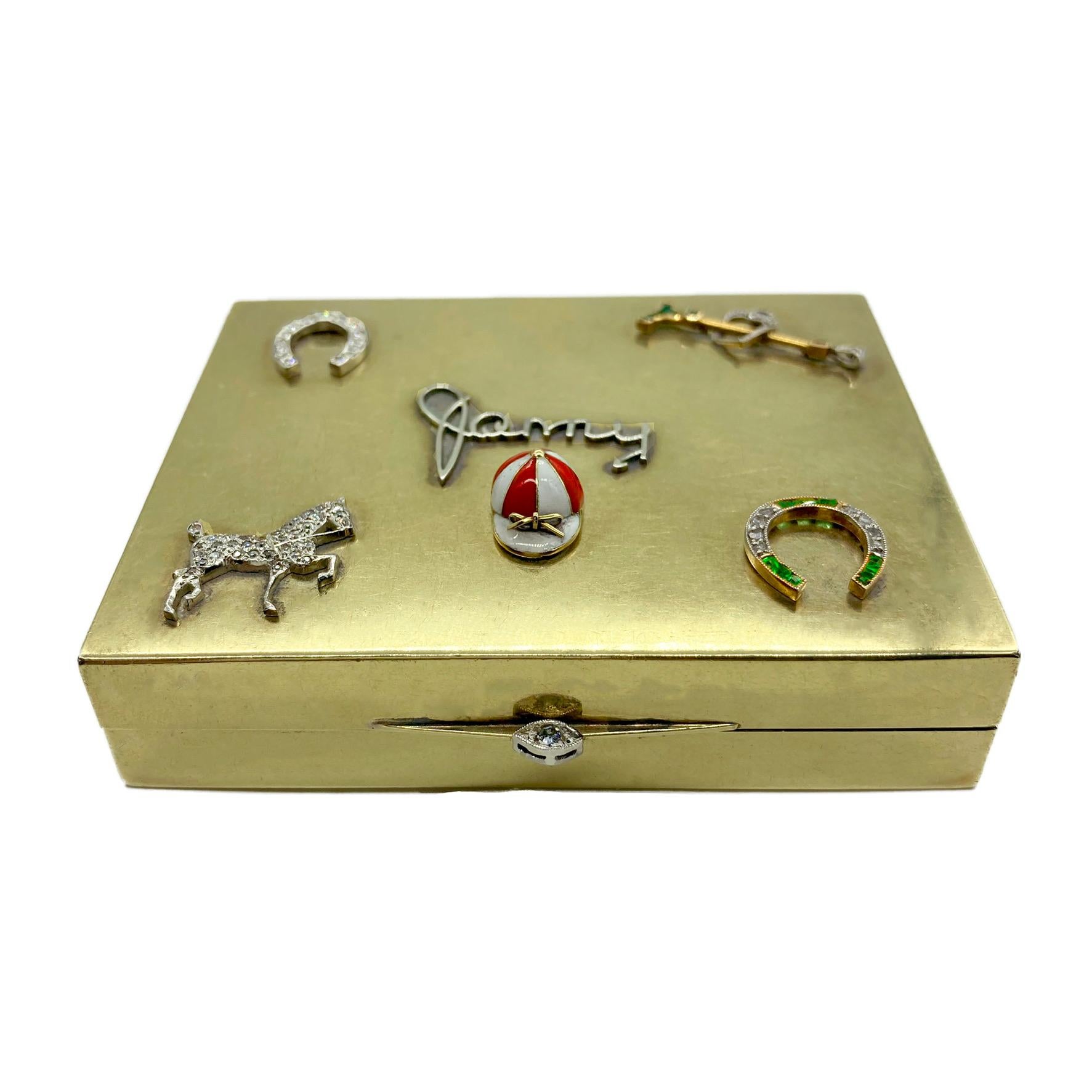 A retro 14 karat yellow gold and sterling silver box featuring a polo theme. Decorated with two horseshoes, a horse, and a polo mallet, all encrusted with diamonds and emeralds. Centering the name “Jenny” with an enamel polo hat beneath and the