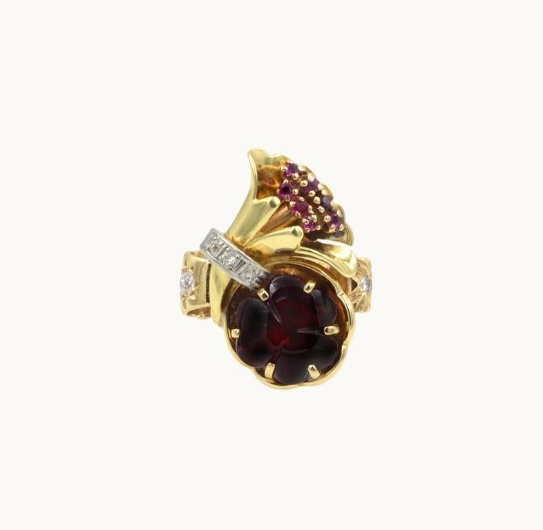 A vintage Retro ring in 14 karat yellow gold from circa 1950s.  This ring features a carved garnet in the shape of a 3-clover accented by diamonds and rubies.

Currently a US size 6.5 and easily adjustable.

This ring measures approximately 0.40