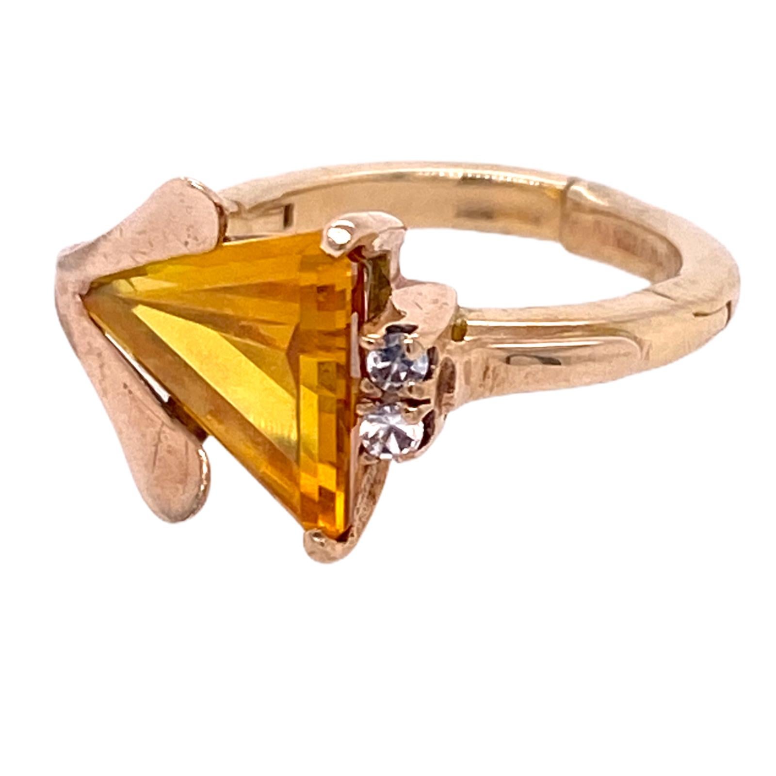 Retro citrine diamond ring fashioned in 14k yellow gold. The triangular cut citrine gemstone is set east to west and features 2 single cut diamonds weighing .16 carat total weight. The ring measures 11.5 mm in width and is currently size 5. A