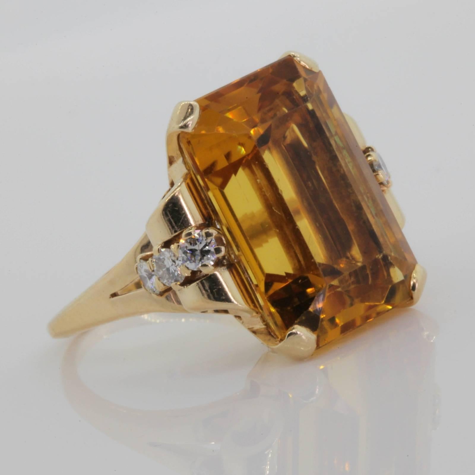 This vibrant Retro ring is fabricated in 14KT yellow gold, and features a beautiful golden-orange cut corner, emerald cut Citrine.  The approx. 20.00 carats Citrine is set in a four fluted prong setting with a soft swirl design on each side. 