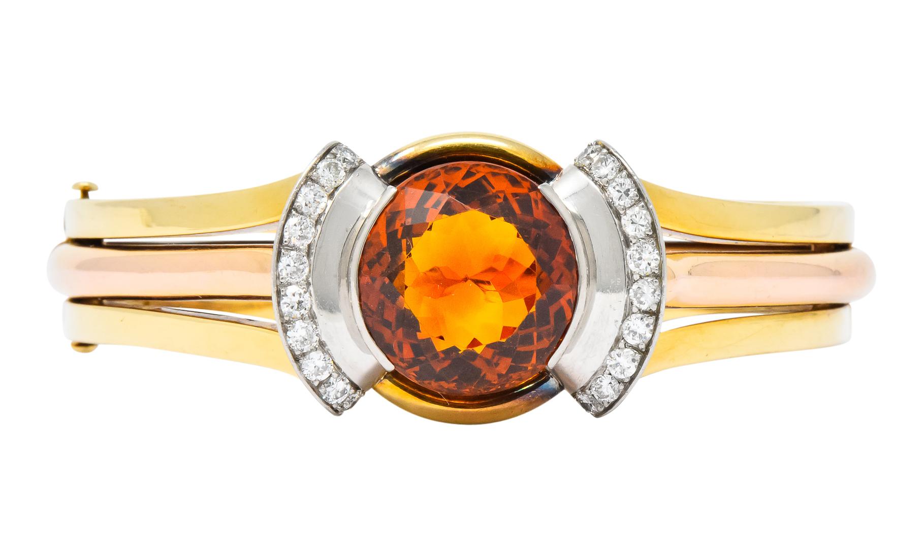 Centering a round mixed cut citrine measuring approximately 17.0 mm, transparent medium-dark brownish-orange

Half bezel set in flared platinum mounting with bead set with round brilliant cut diamonds weighing approximately 0.60 carat total, H/I