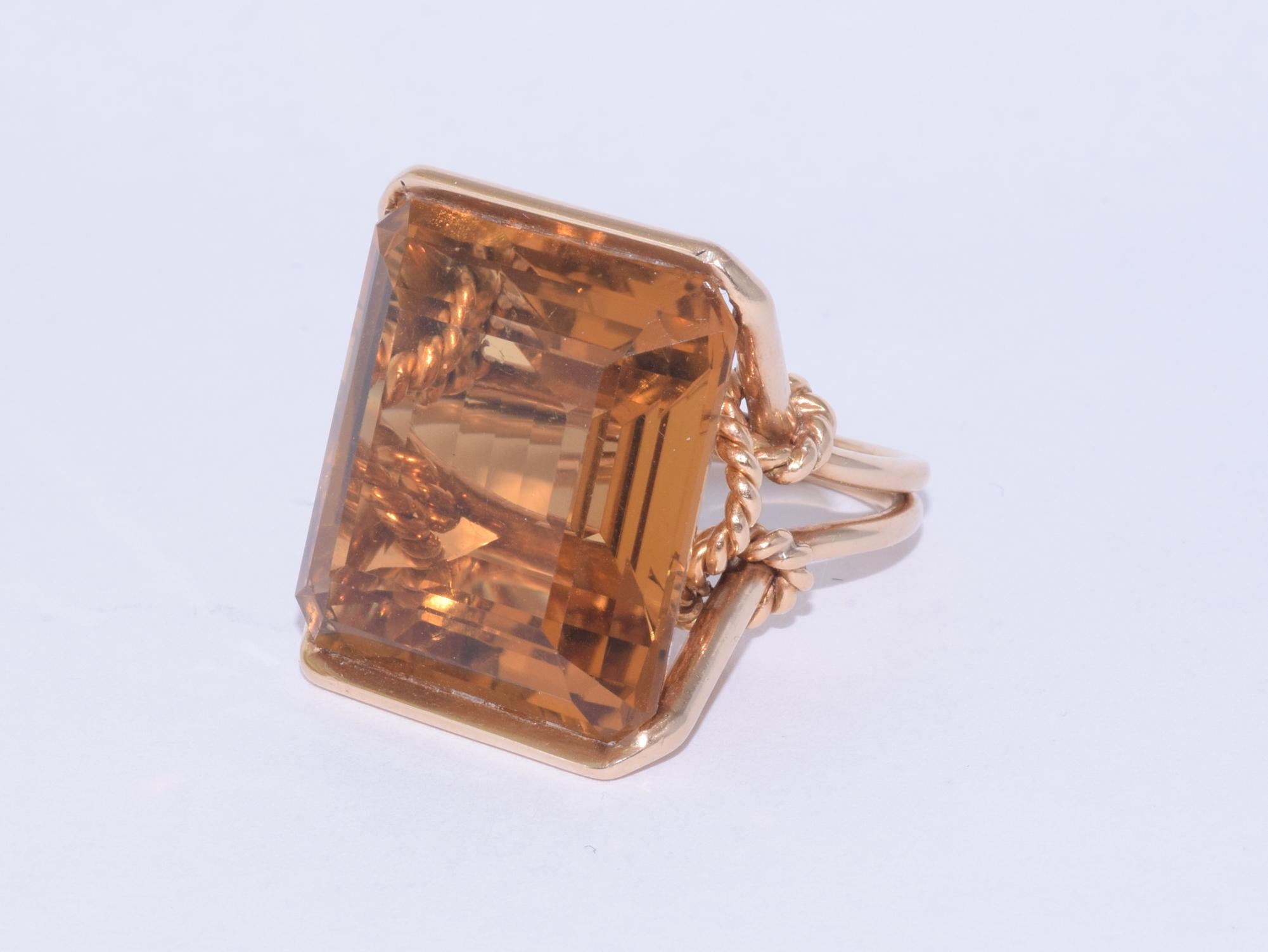 An impressive emerald cut citrine weighing 42.84 carats is mounted in 18 karat yellow gold with decorative knotted rope motifs. Finger size 6.5, 
14.47mm height off finger. The top of the ring measures approximately 25.3 x 20.9mm.