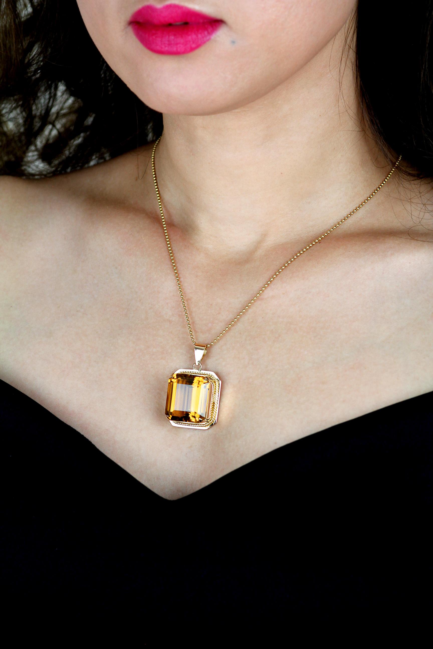 Beautifully composed citrine pendant in 18 carat yellow gold. It features a luxurious glowing fiery yellow orange citrine in a rectangular emerald cut, bordered with a stunning yellow gold rope twist border, and yellow gold pendant bail. The citrine