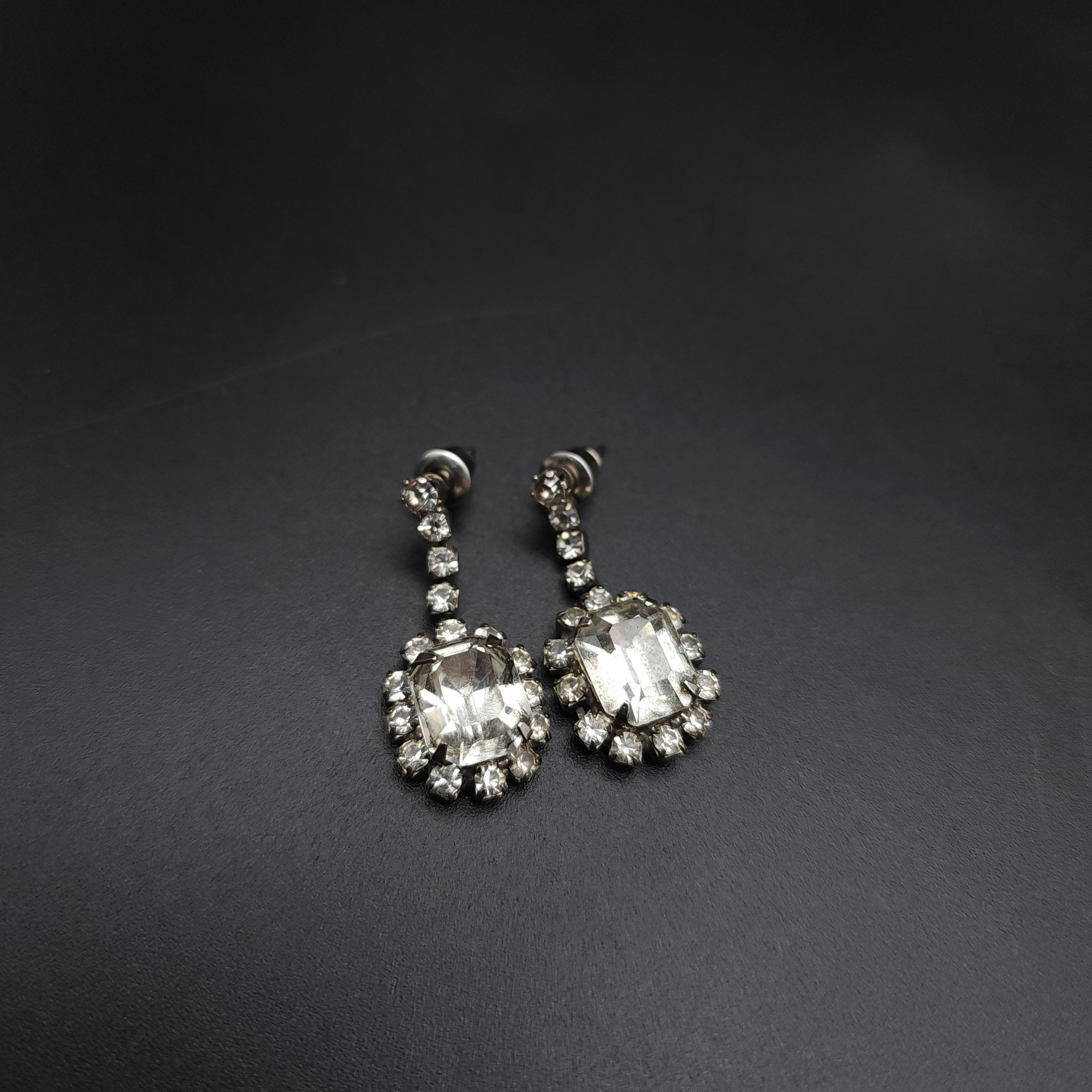 Dimensions: 3 cm length x 1.2 cm width at widest part, each earring

Add a dash of classic glamour to your look with the Retro Clear Crystal Dangle Earrings. These stunning earrings feature a square cut centerpiece, beautifully prong-set to catch