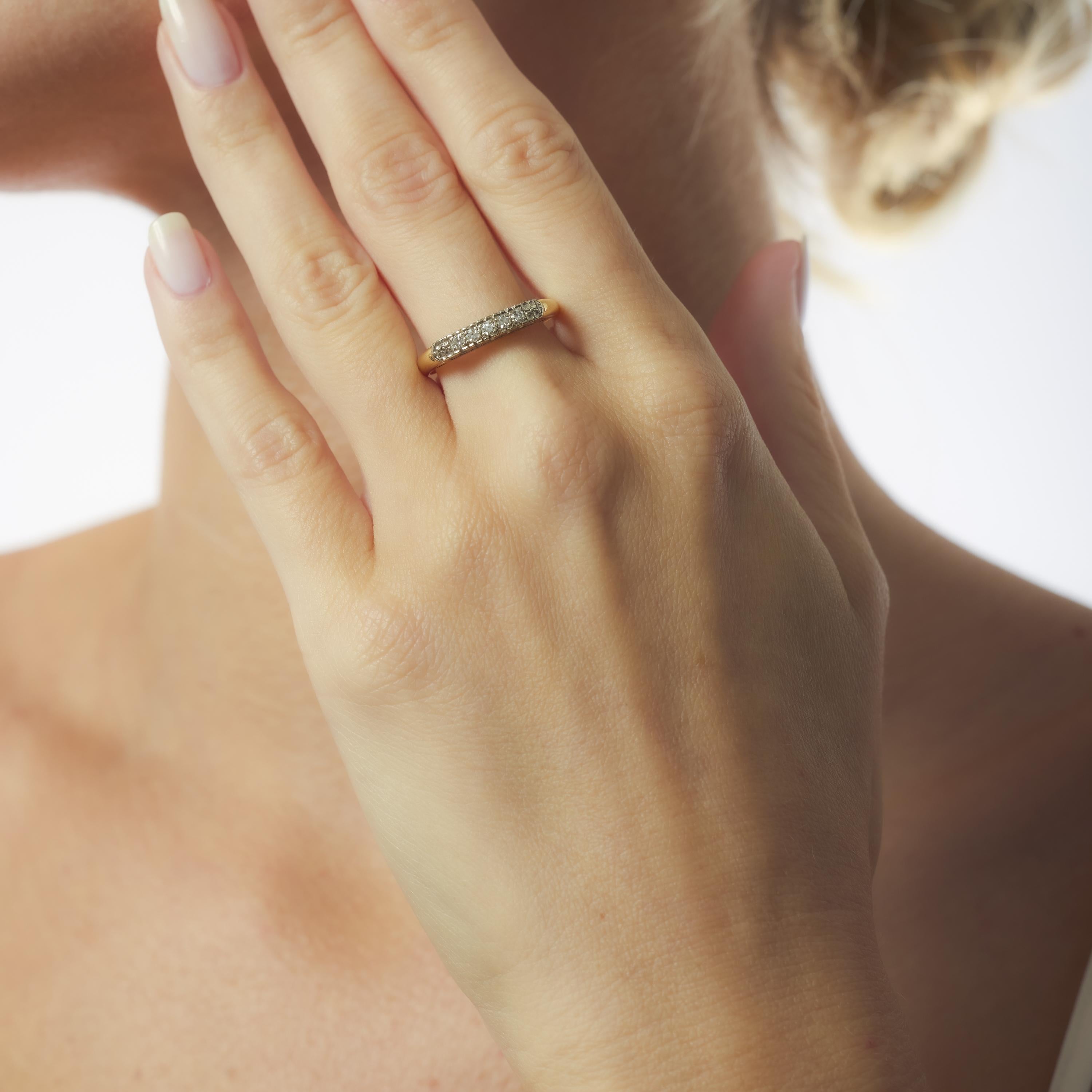 This Retro two-tone gold ring features five sparkling single cut diamonds set in a streamlined 14k yellow and white gold design. Crafted in the 1940s, it blends vintage charm with mid-century elegance in a versatile and timeless band.