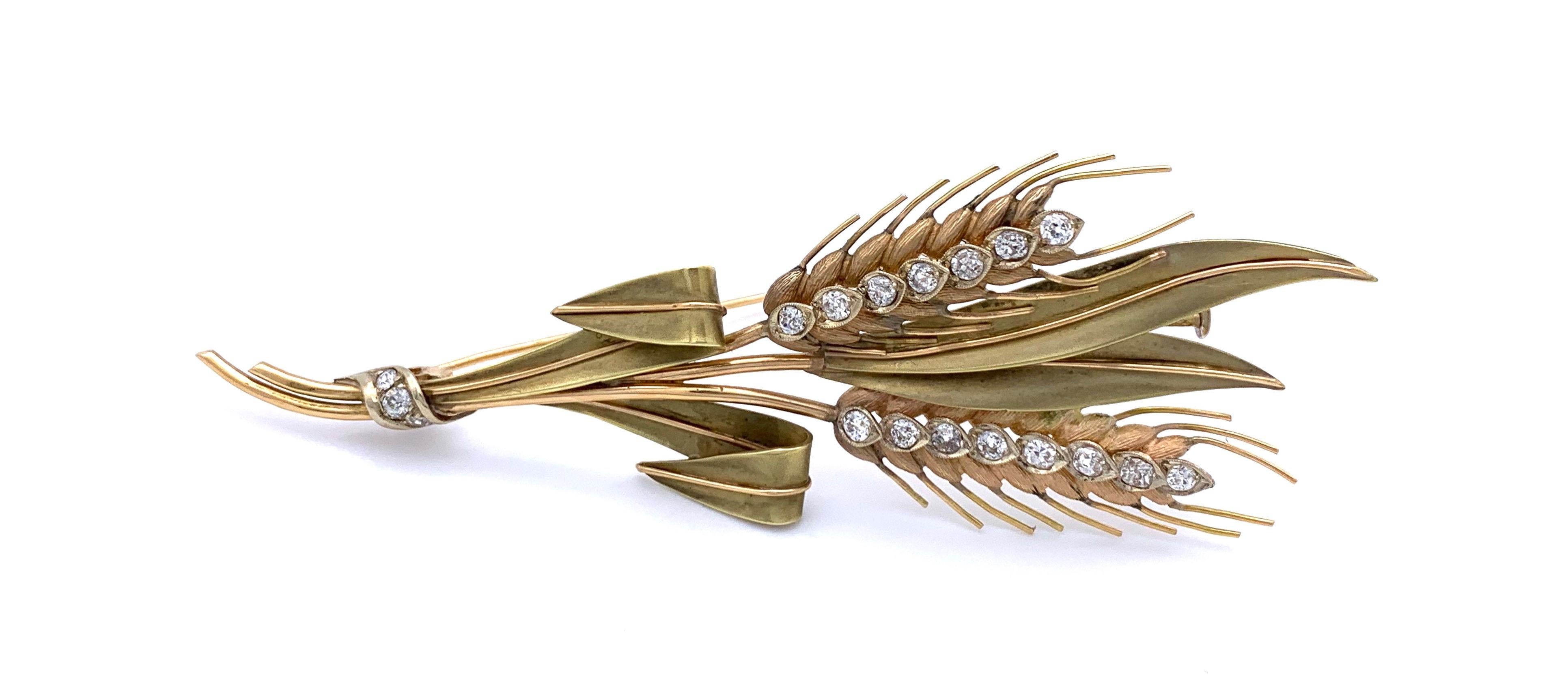 Retro brooch in the shape of a two ears held together by a diamond set ribbon. One ear is set with 7 diamonds, the other with 8 diamonds. The stems of the ear leaves are tied together into a bundle and the rope is set with three diamonds. The brooch