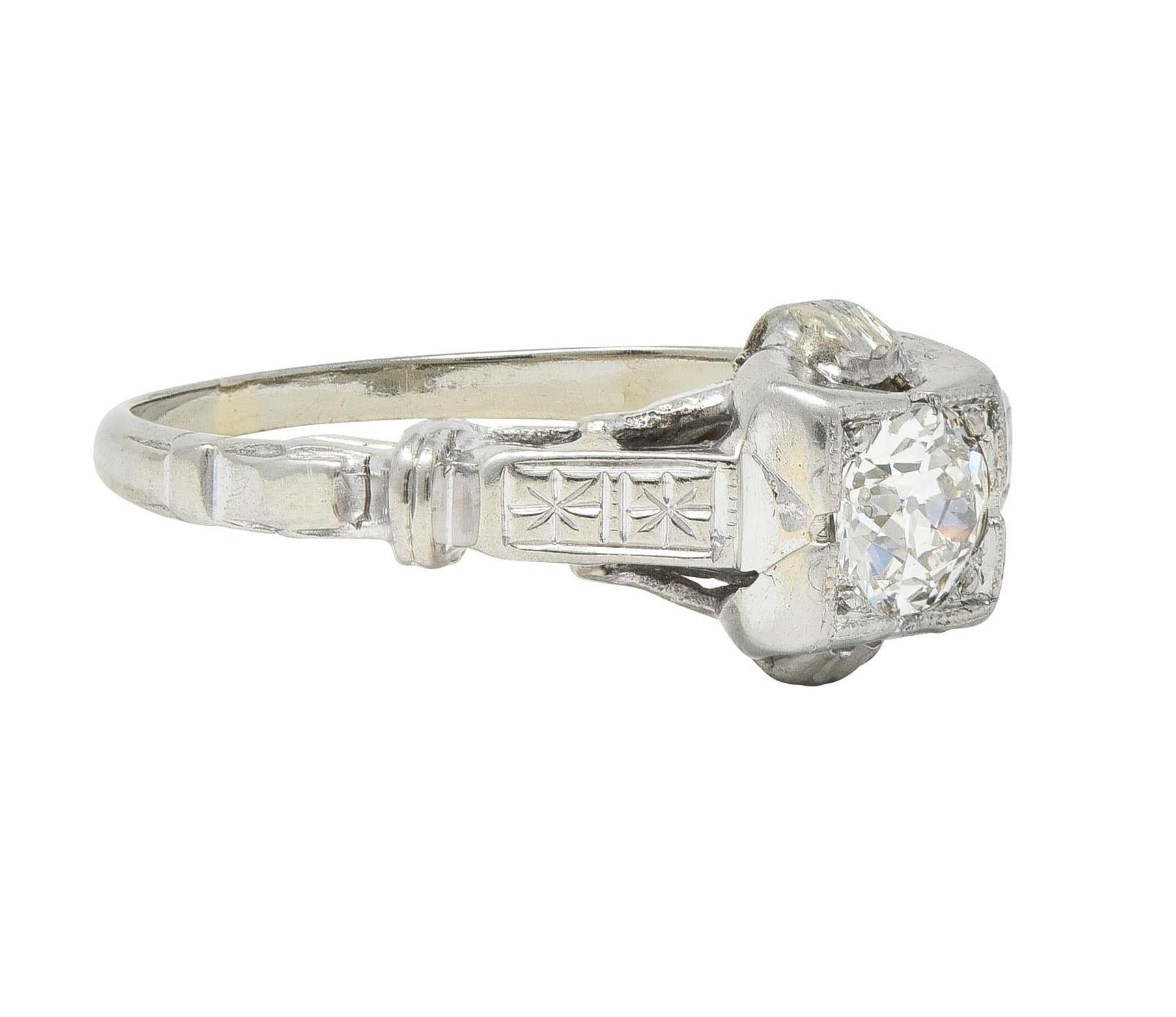 Centering an old European cut diamond weighing approximately 0.40 carat 
J color with VS2 clarity - bead set in a grooved square form head
With grooved buckle motif profile - flanked by cathedral shoulders
Engraved with orange blossom motif 
Tested
