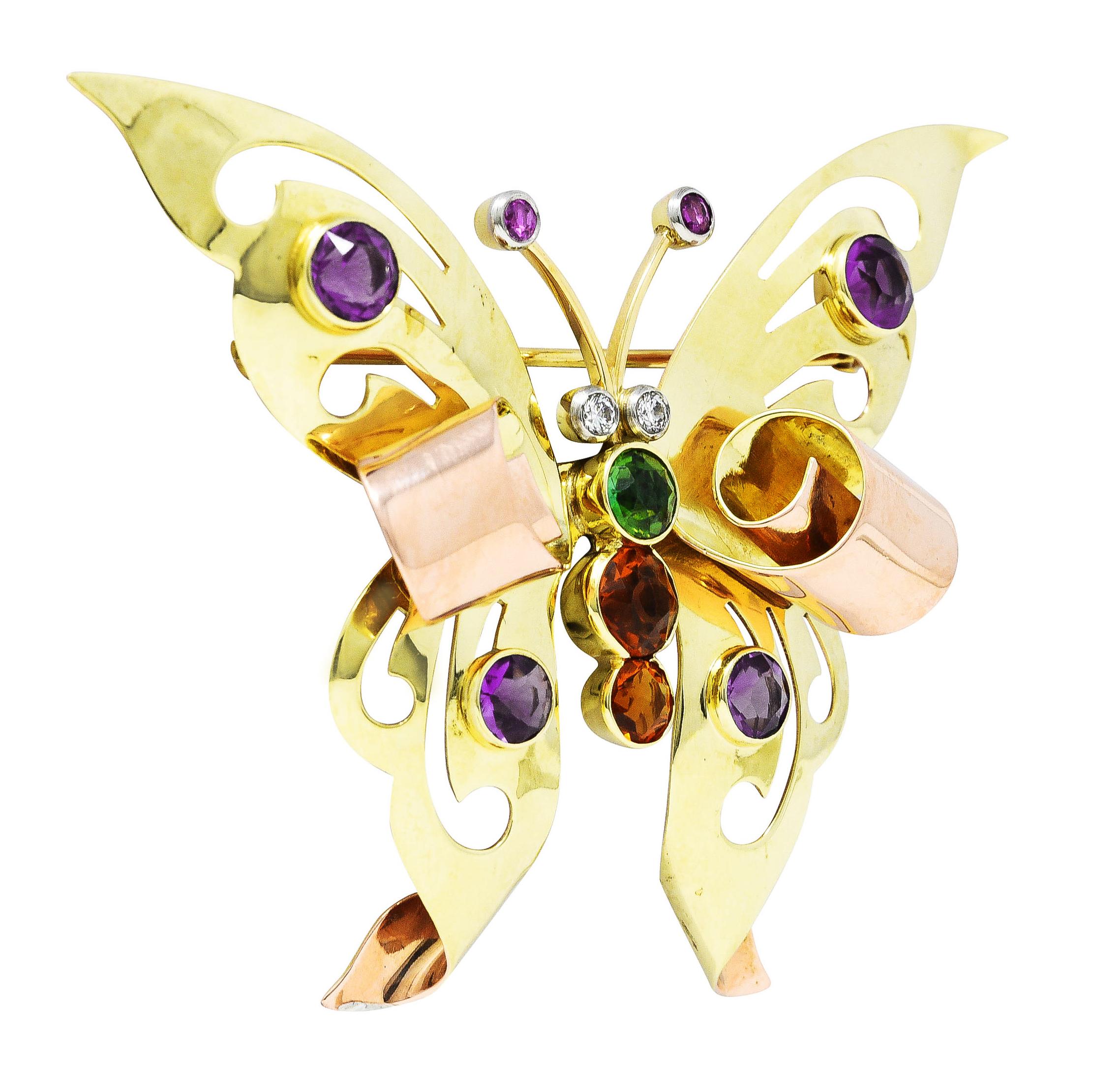 Brooch is designed as a butterfly with pierced yellow gold wings with scrolling rose gold tips- accented by amethyst. Bezel set round cut and ranging in size - transparent reddish-purple in color with medium saturation. Body is comprised of bezel