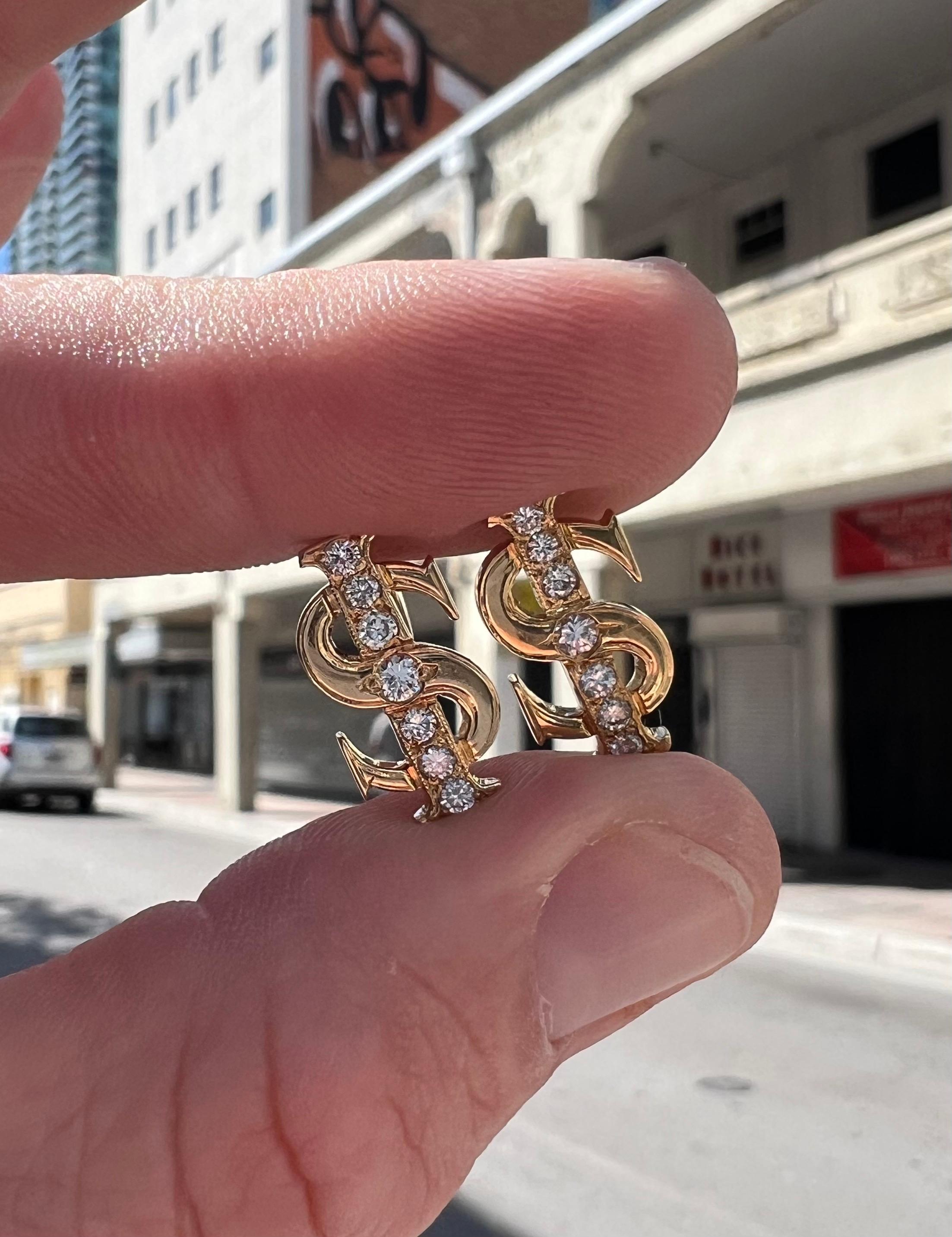Excellent pair of solid 18k yellow gold cuff links. The pair depict dollar signs with a row of round brilliant cut diamonds set along the center. The diamonds in the pair weigh approximately 0.75 carat and display white color and Vs/Si clarity.
The