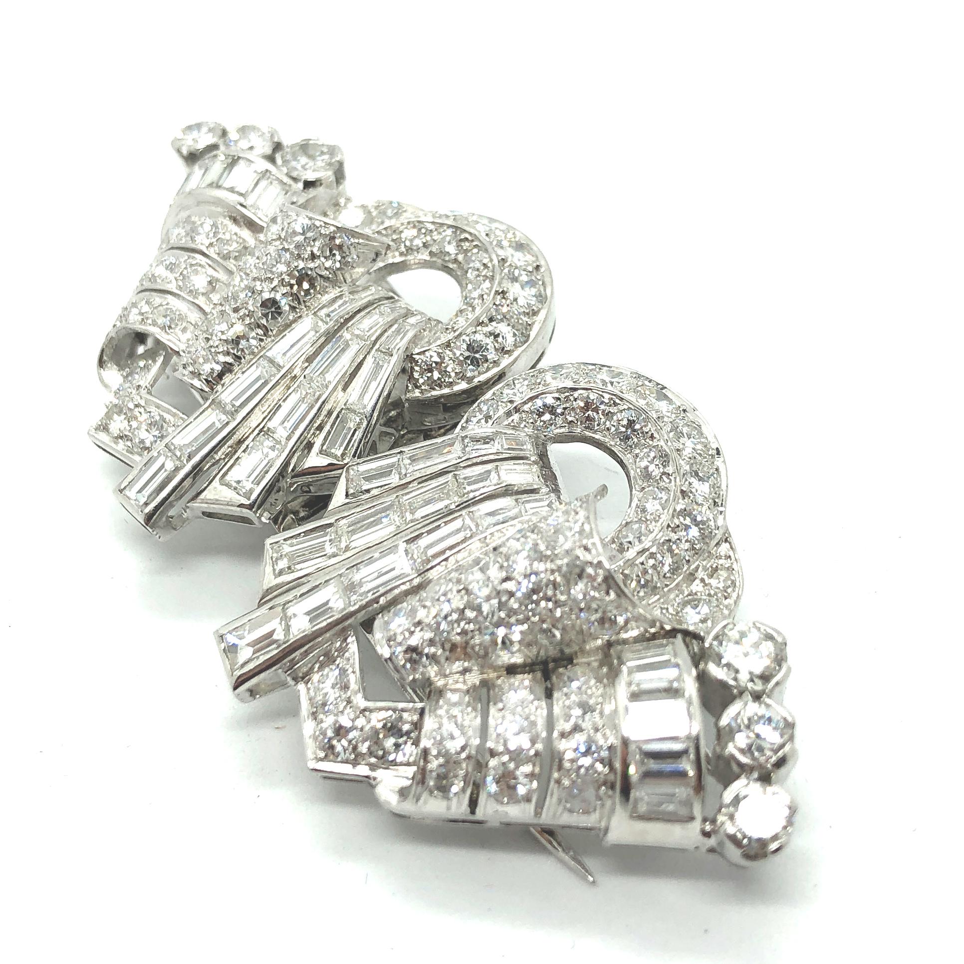 A diamond double clip brooch in platinum, Art Deco, ca. 1940s. The clips are set with round brilliant cut diamonds and diamond baguettes, following a very artistic design. The total diamond weight is circa 10 carats of very fine quality diamonds E/F
