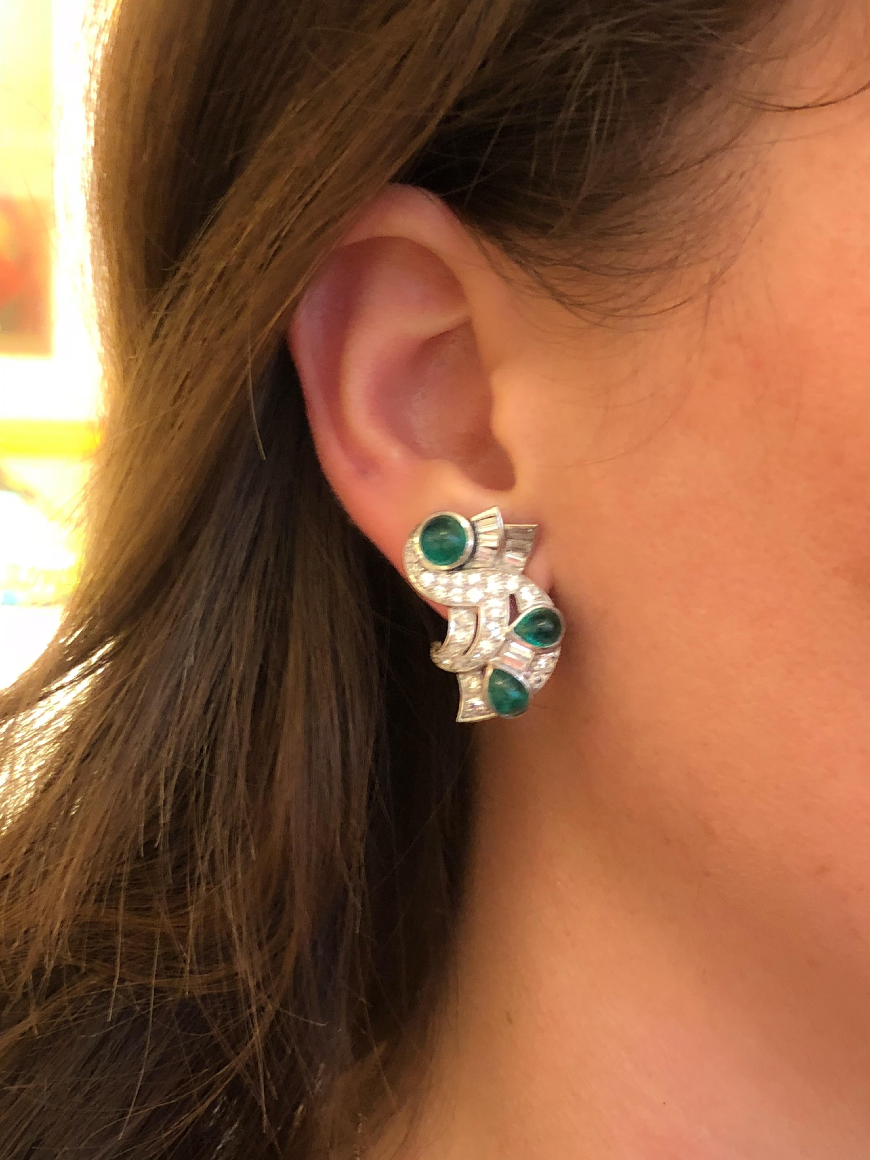 A pair of Retro platinum earrings with diamonds and emeralds. The earrings have 50 round-cut diamonds with an approximate total weight of 2.70 carats, and 16 baguette cut diamonds with an approximate total weight of 1.60 carats. The total