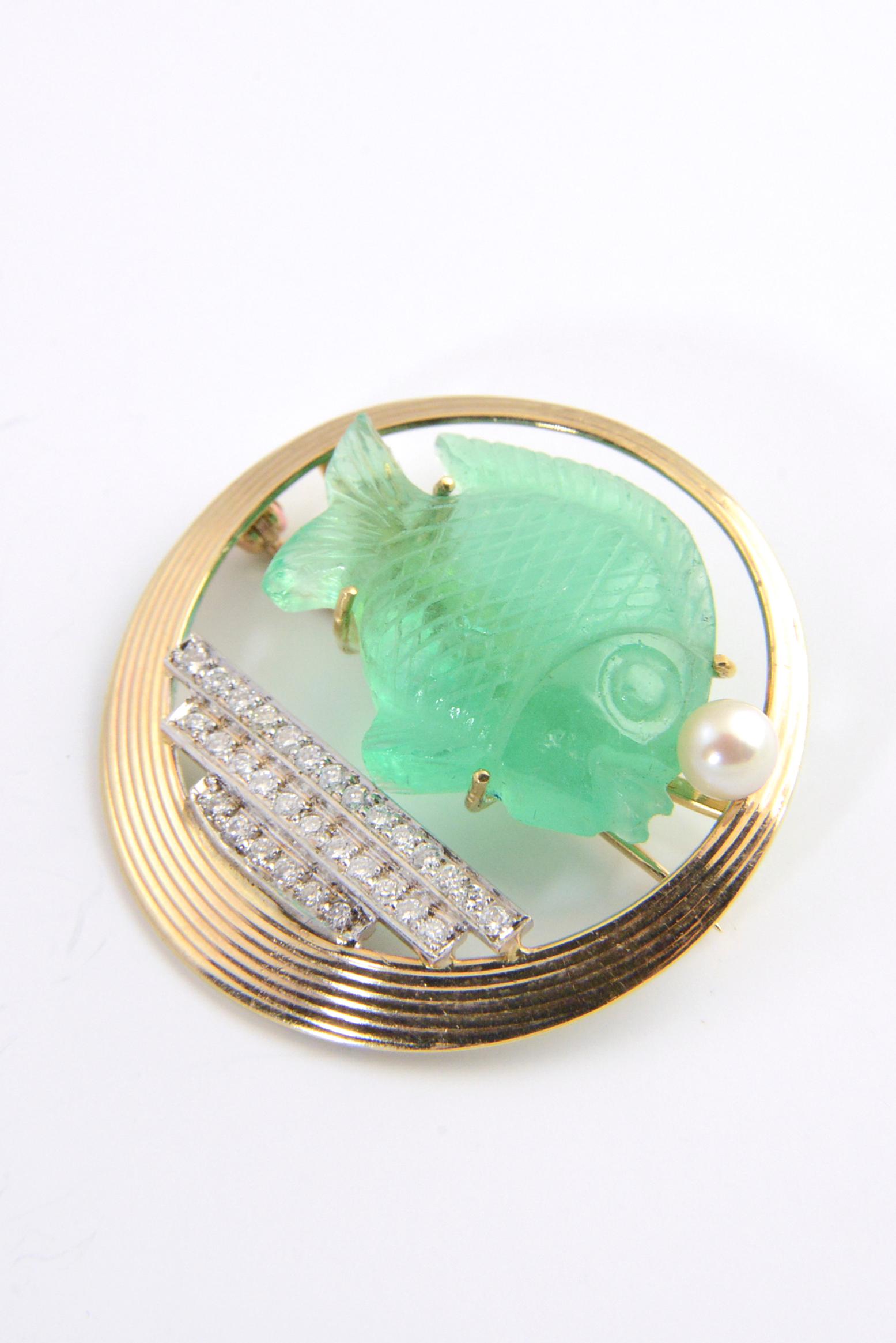 1940s Fish bowl circle brooch featuring a carved emerald fish blowing a pearl bubble in a diamond sea. The frame is 14K yellow gold. 
Marked: 14K T. Attributed to Tiffany & Co.