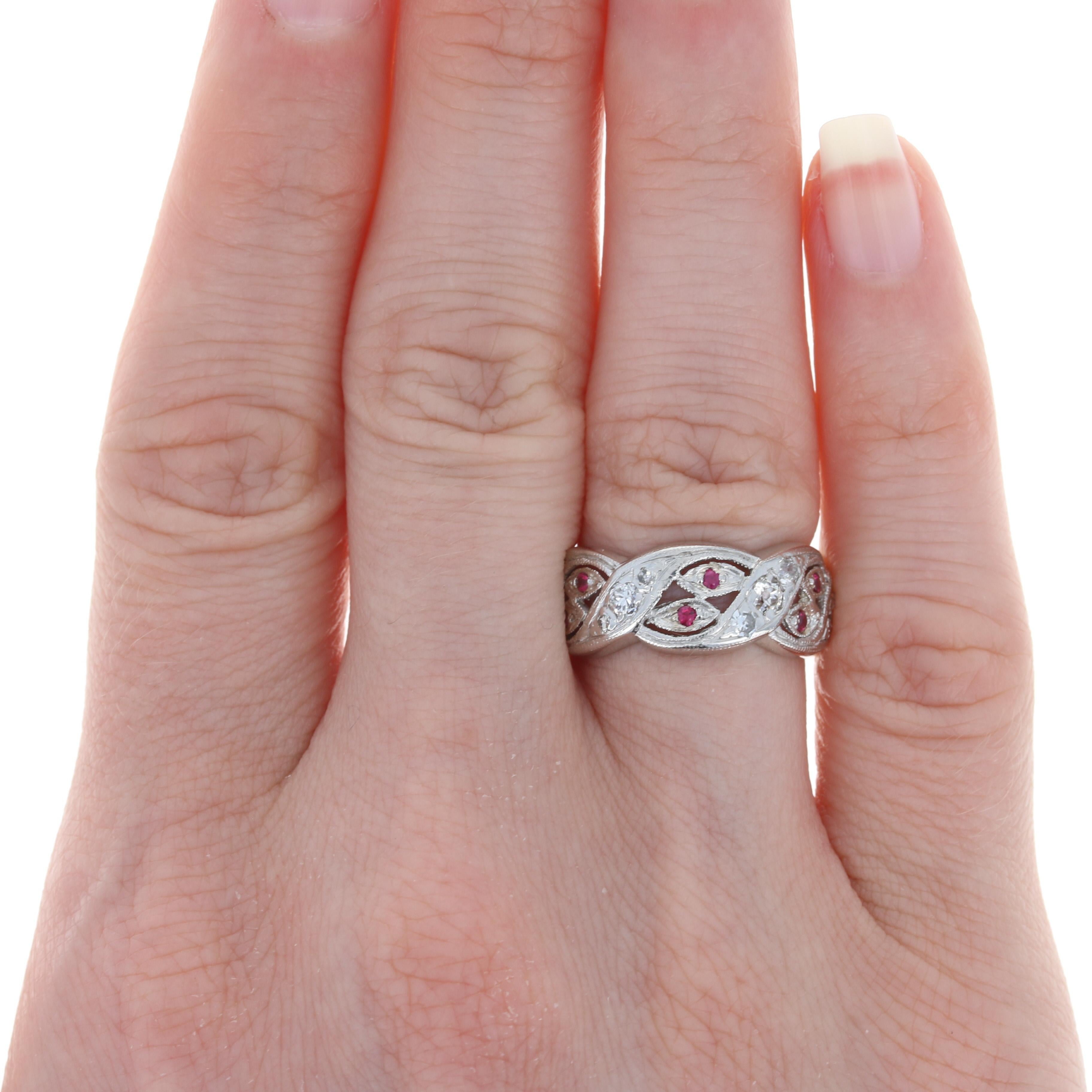 Retro romance to light up the night! Created in the 1940s - 1950s, this stunning platinum band features a meaningful eternity silhouette graced by a wrapped ribbon design set with a sparkling array of white diamonds and majestic rubies that are