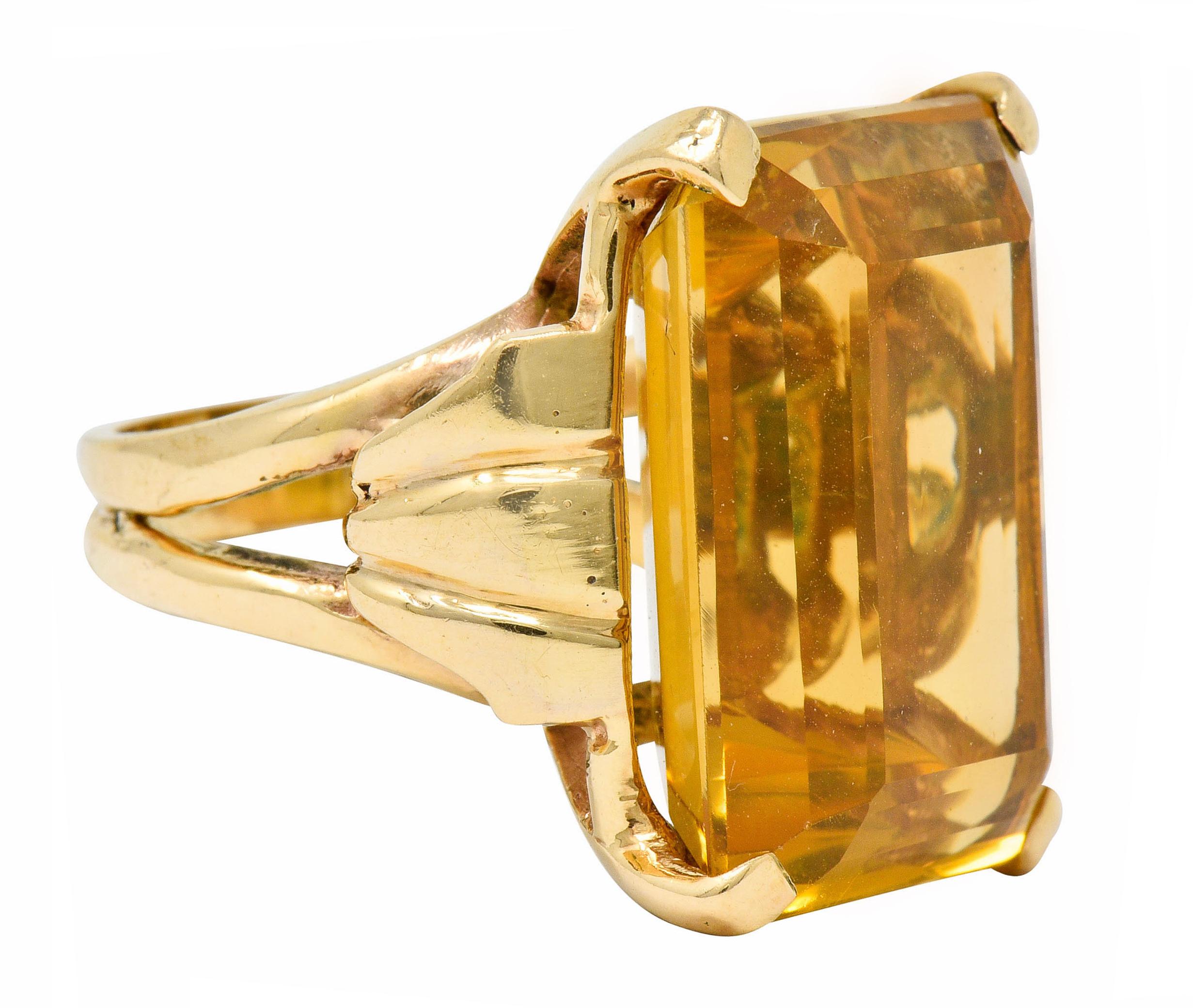Centering a basket set emerald cut citrine measuring approximately 22.5 x 16.8 mm

Transparent with sunny very slightly orangey-yellow color, even in distribution

Completed by a split shank featuring scrolled shoulder motif

Stamped 14K for 14