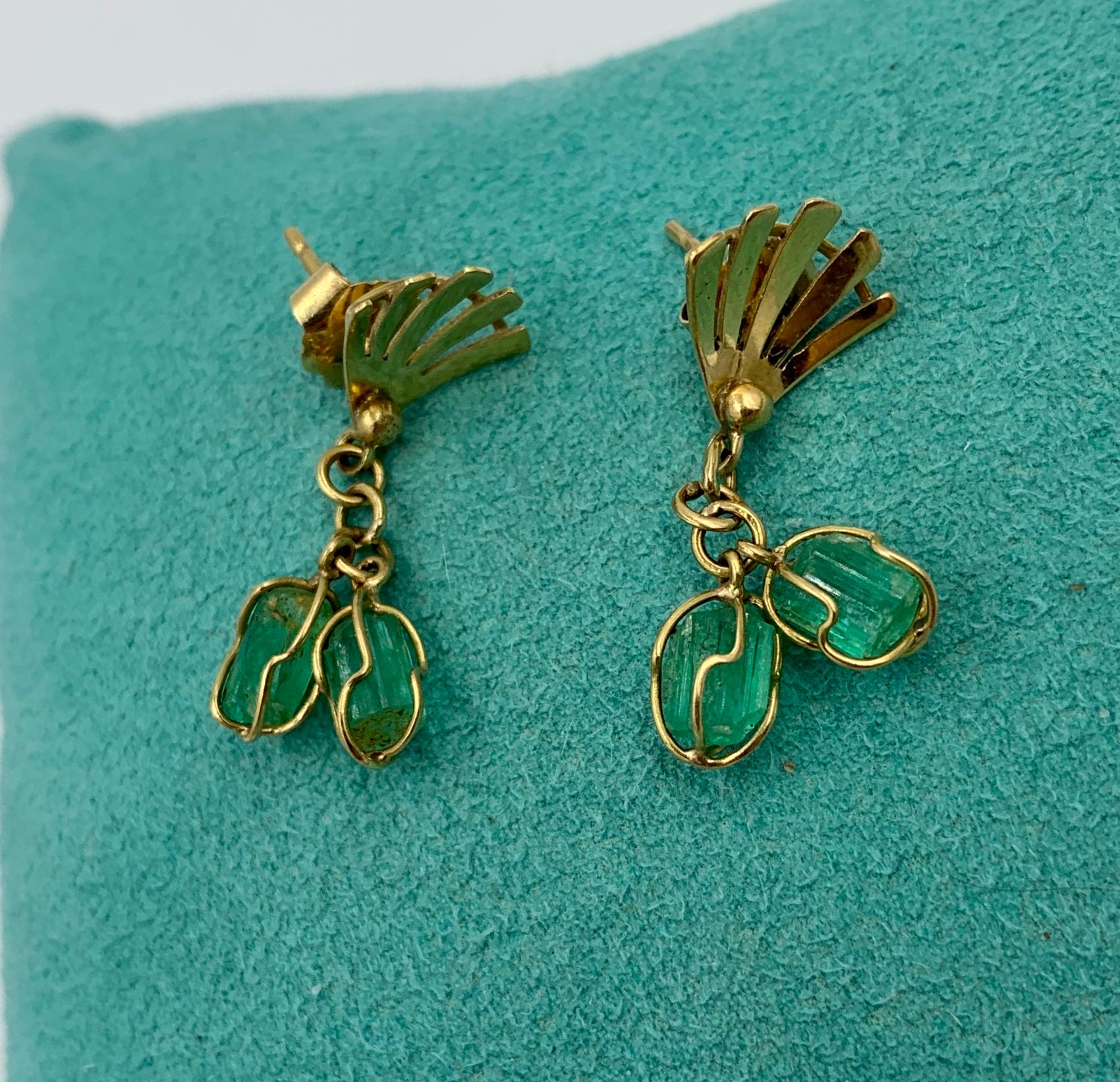 Si tratta di uno splendido paio di orecchini pendenti Retro Emerald con quattro gemme di smeraldo tagliate grossolanamente di grande bellezza incastonate in un design a filo d'oro 18 carati.  Gli smeraldi sono appesi a una corona a ventaglio.  Gli