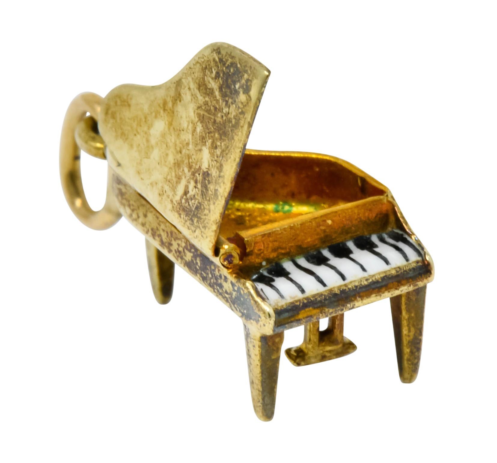 Charm designed a piano with stylized glossy black and white enamel keys

Hinged piano lid lifts up to reveal two bright red enamel hearts

Stamped 14KT for 14 karat gold

Completed by jump ring bale

Circa: 1950s

Measures: 3/4 x 5/16 inch

Total