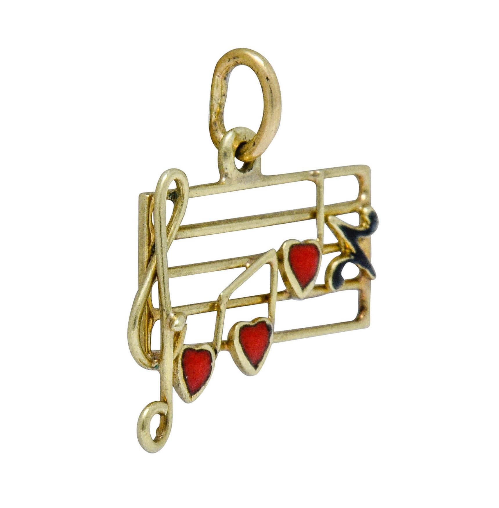 Designed as musical scale made of polished gold horizontal bars

With twisted gold wire G clef followed by a black enamel rest note and musical notes accented with bright red enamel hearts

Measures: 5/8 x 1/2 inch

Total weight: 1.0 grams

Joyful.