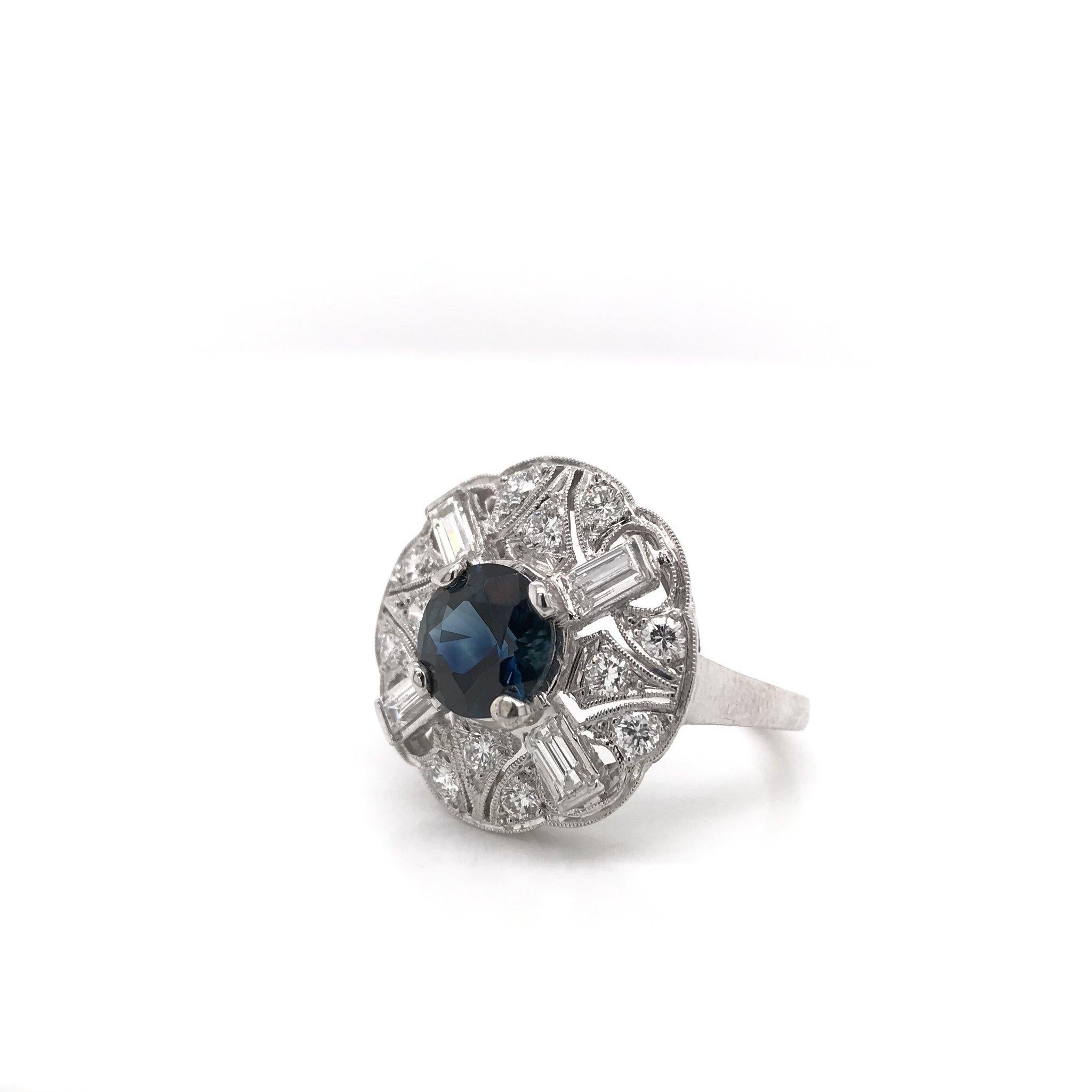 This gorgeous platinum cocktail ring was crafted sometime during the Retro design era ( 1940-1960 ). The center stone is a round 1.82 carat blue sapphire. The setting features fine milgrain accents, intricate geometric motif filigree, 12 round cut