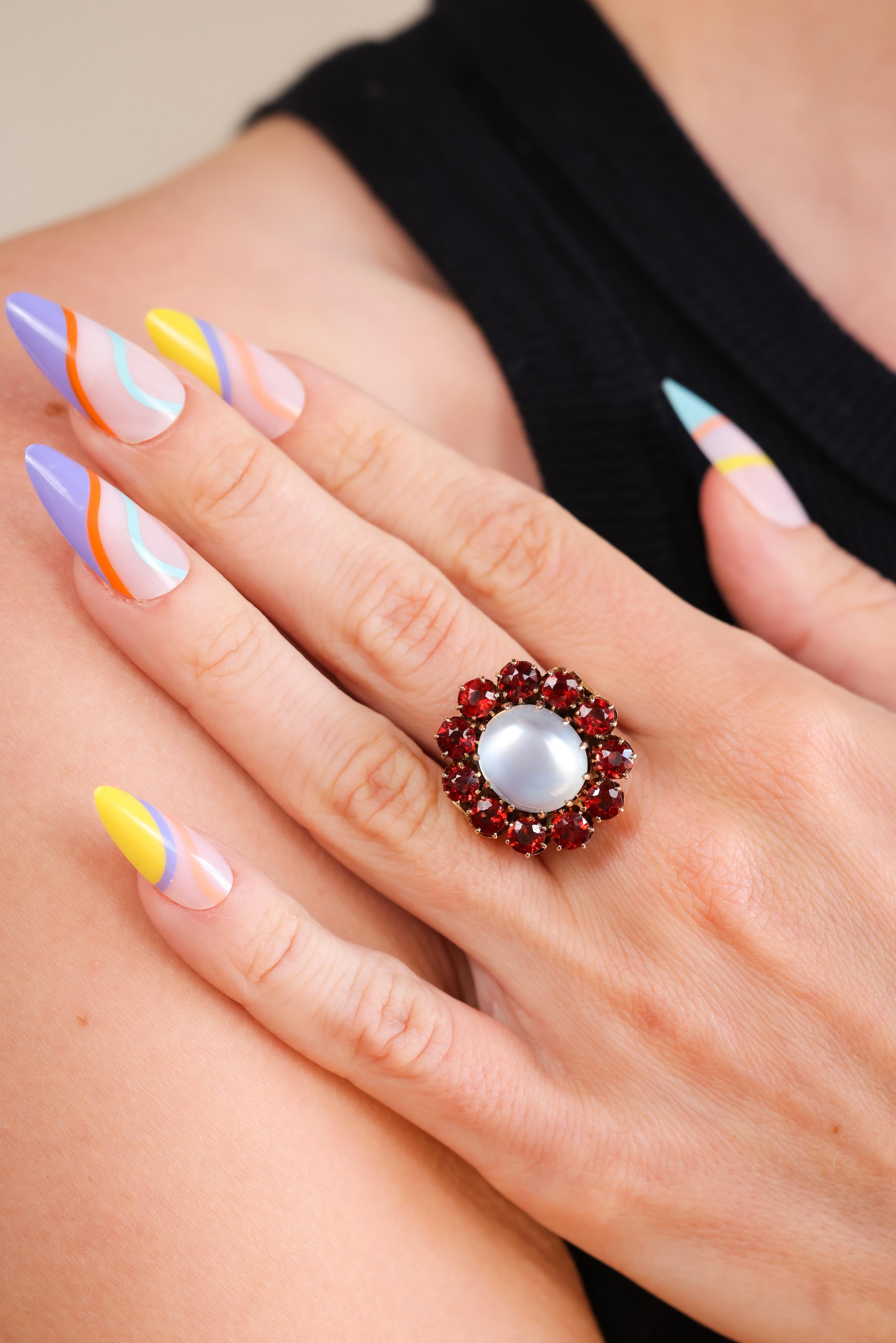 Dies ist ein unvergessliches Retro-Ära (ca. 1940er Jahre) Vintage Mondstein und Granat Cocktail-Ring. Der farbenfrohe Ring zeigt einen wunderschönen ovalen Cabochon-Mondstein mit den Maßen 13,40 mm x 12,20 mm und einem Gewicht von ca. 8,75ct.
