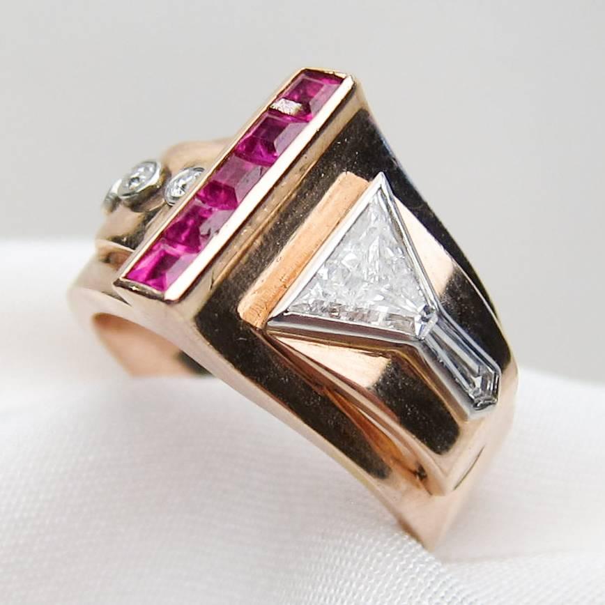 Circa 1940. This striking Retro Era ring sparkles with four, step-cut rubies weighing .25 carats total. The ring is accented with one triangular-cut diamond, one shield-shaped diamond, and three old European-cut diamonds weighing .44 carats total,