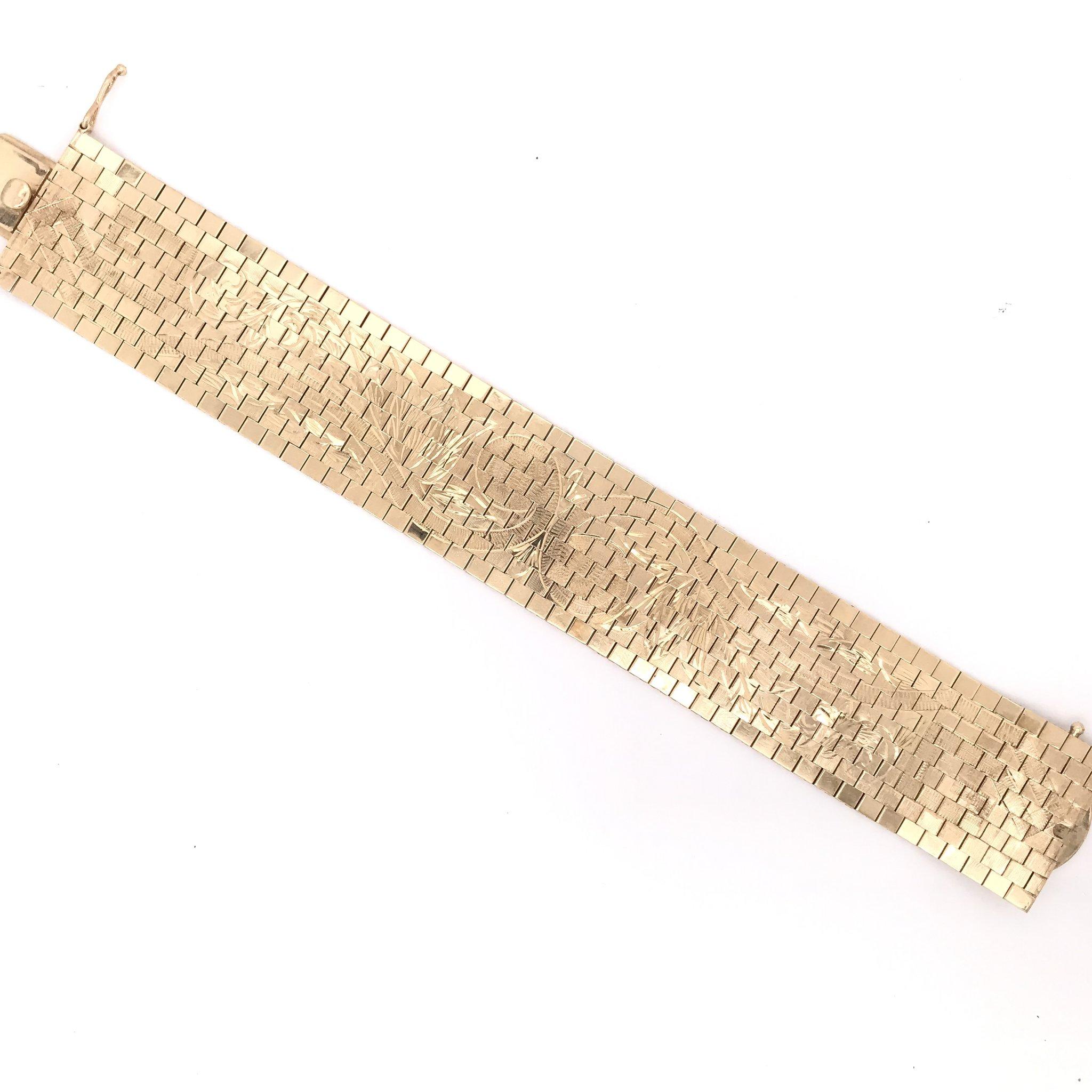 This wide gold bracelet is an estate piece. The bracelet is 14k gold and crafted in the Italian gold mesh style although it does not specify that it is Italian made. The smooth 14K gold links feature extensive floral engravings. This bracelet
