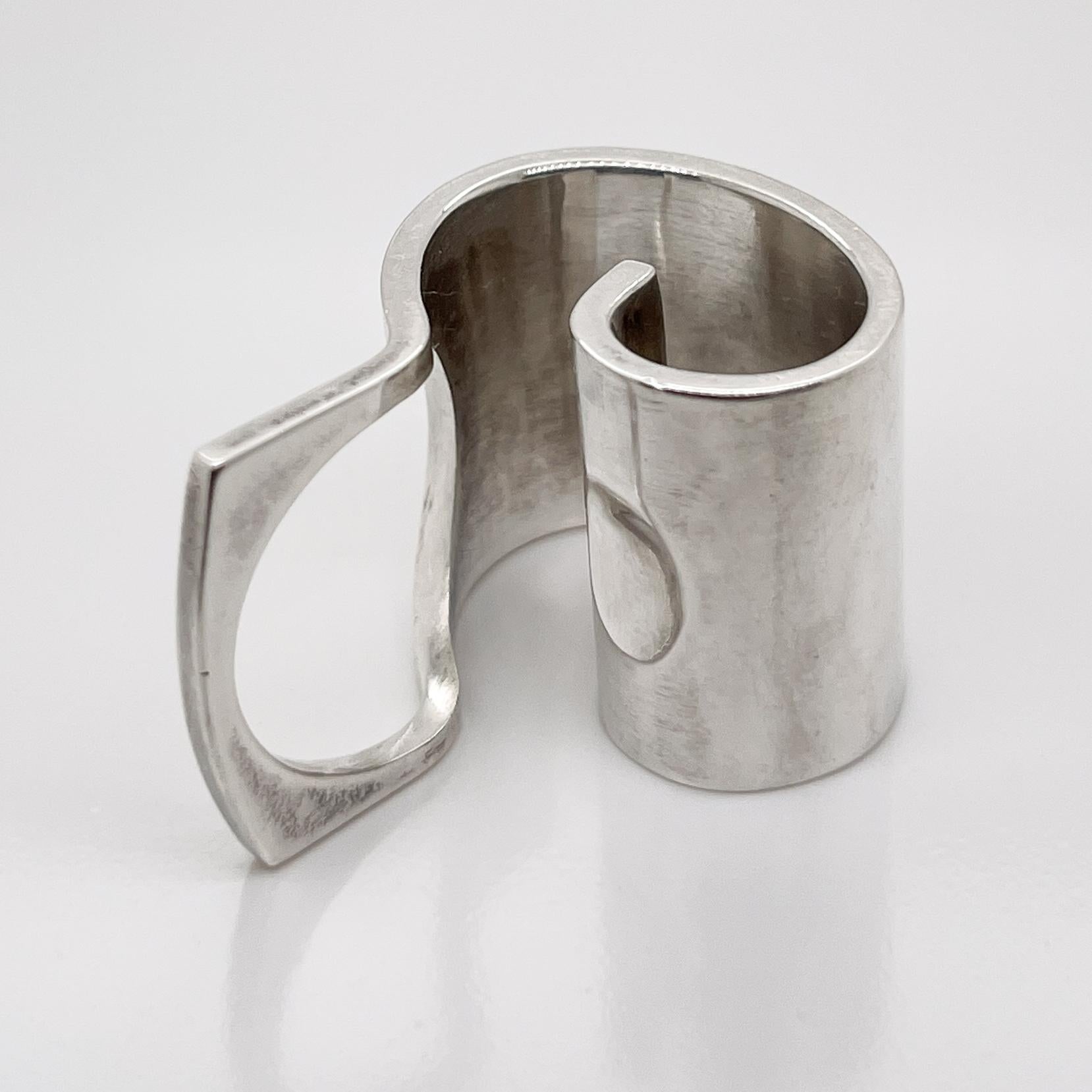 Une très belle bague moderniste finlandaise en argent sterling.

Par Pekka Piekainen.

Fabriqué à partir d'une épaisse galette d'argent sterling enroulée en spirale.

Le doigt se glisse dans une ouverture à une extrémité et la spirale repose