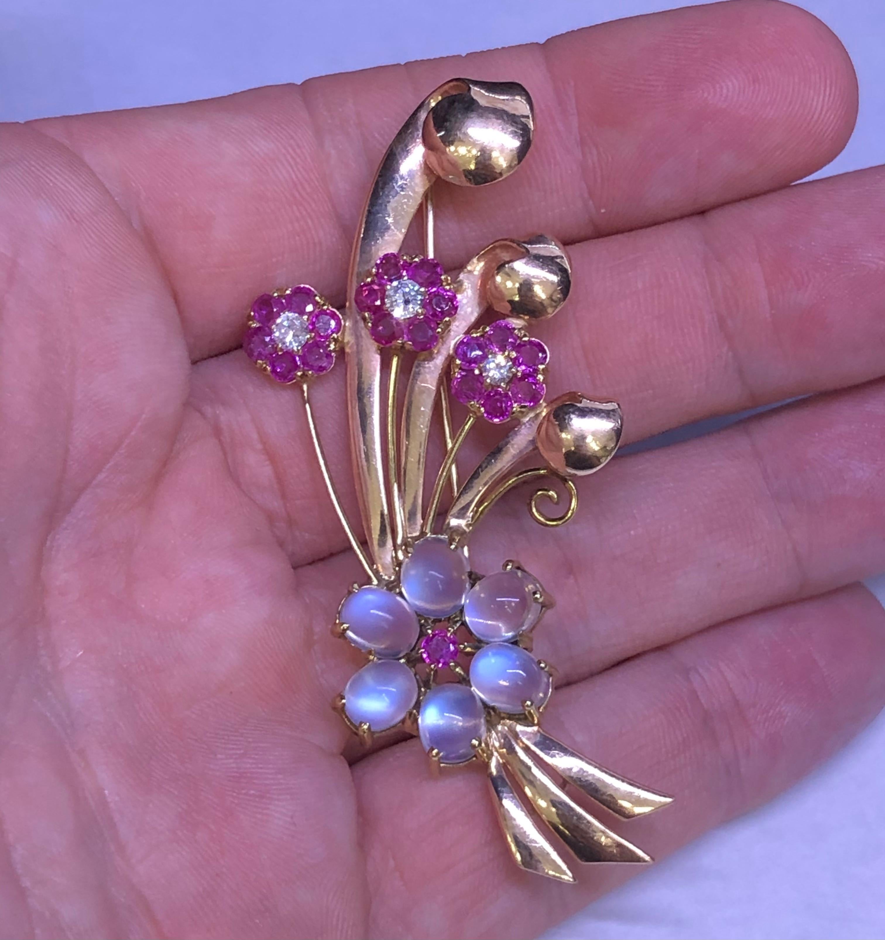 Beautifully crafted floral spray brooch crafted in 14k yellow gold. This fantastic design is set with gemstones throughout.  The brooch is set natural rubies that display a vivid red color that almost pop off the design, accenting the ruby gemstones