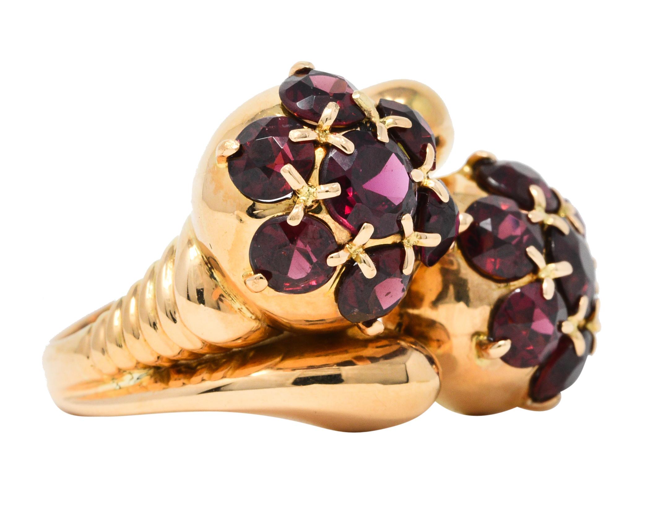 Bypass style ring features two substantial clusters of garnet with stylized criss-cross prongs

Garnets are round cut and a very well matched medium dark purplish red color

Completed by split shoulders with ribbed detailing and a bright