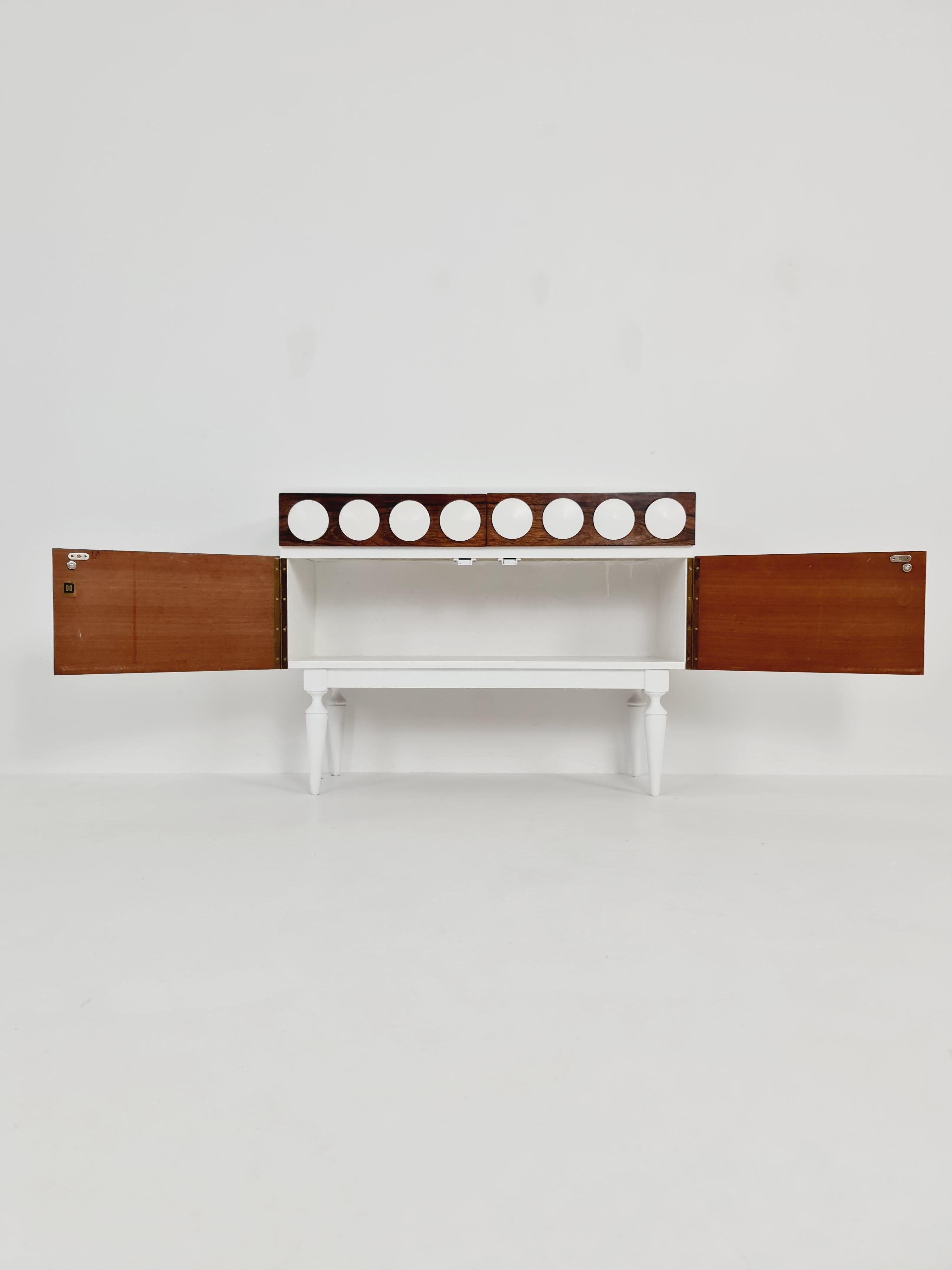 Retro German Rosewood & white Sideboard, 1970s

Design year: 1970s
 
Dimensions: 32   D x 82 W x 62  H cm

It is in good vintage condition, however, as with all vintage items some minor wear marks should be expected.

Please inquiry for prices to