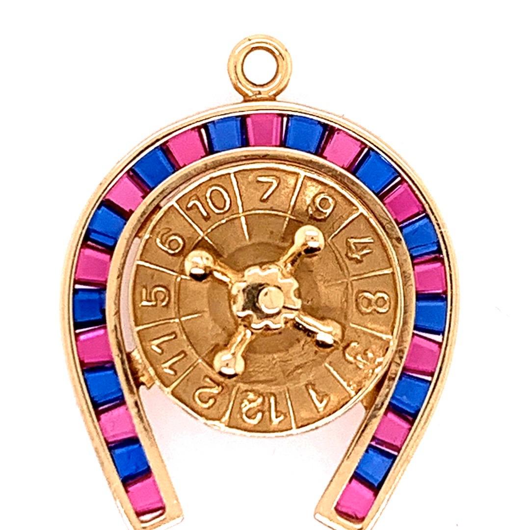 Modern 14k Yellow Gold Horseshoe Pendant set with 25 Natural Rubies & Sapphires weighing approximately 2.2 Carats. The centerpiece of this pendant is a gold roulette wheel that spins. 
 
The total weight of the piece is 5.5 grams, chain not