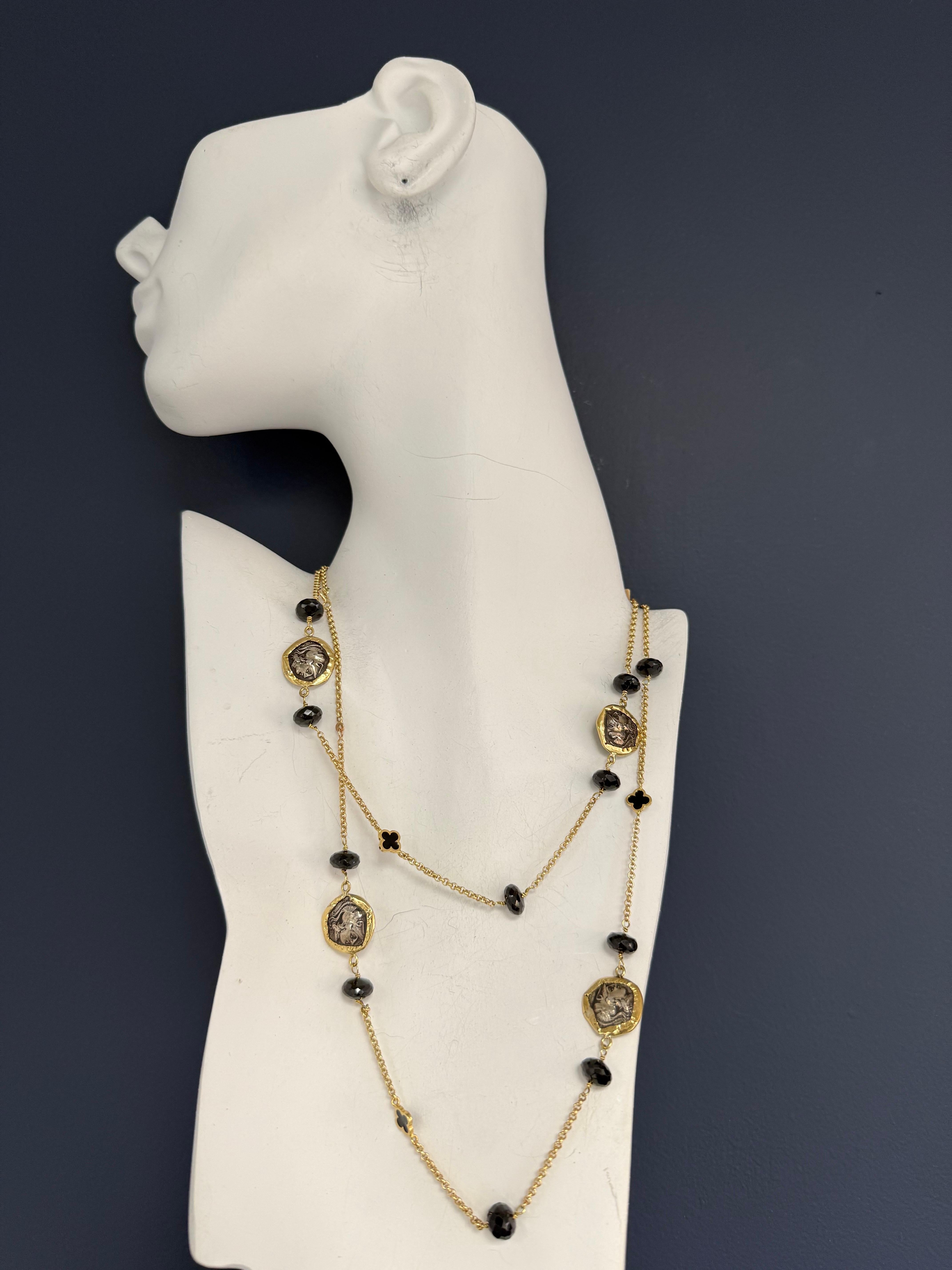 A retro gold statement opera necklace by the renowned jeweler Misento, stamped 585 for 14K gold. The 36-inch necklace features fifteen natural garnets and four double-sided enamel clovers, accented by five ancient Greek Rhodes coins depicting