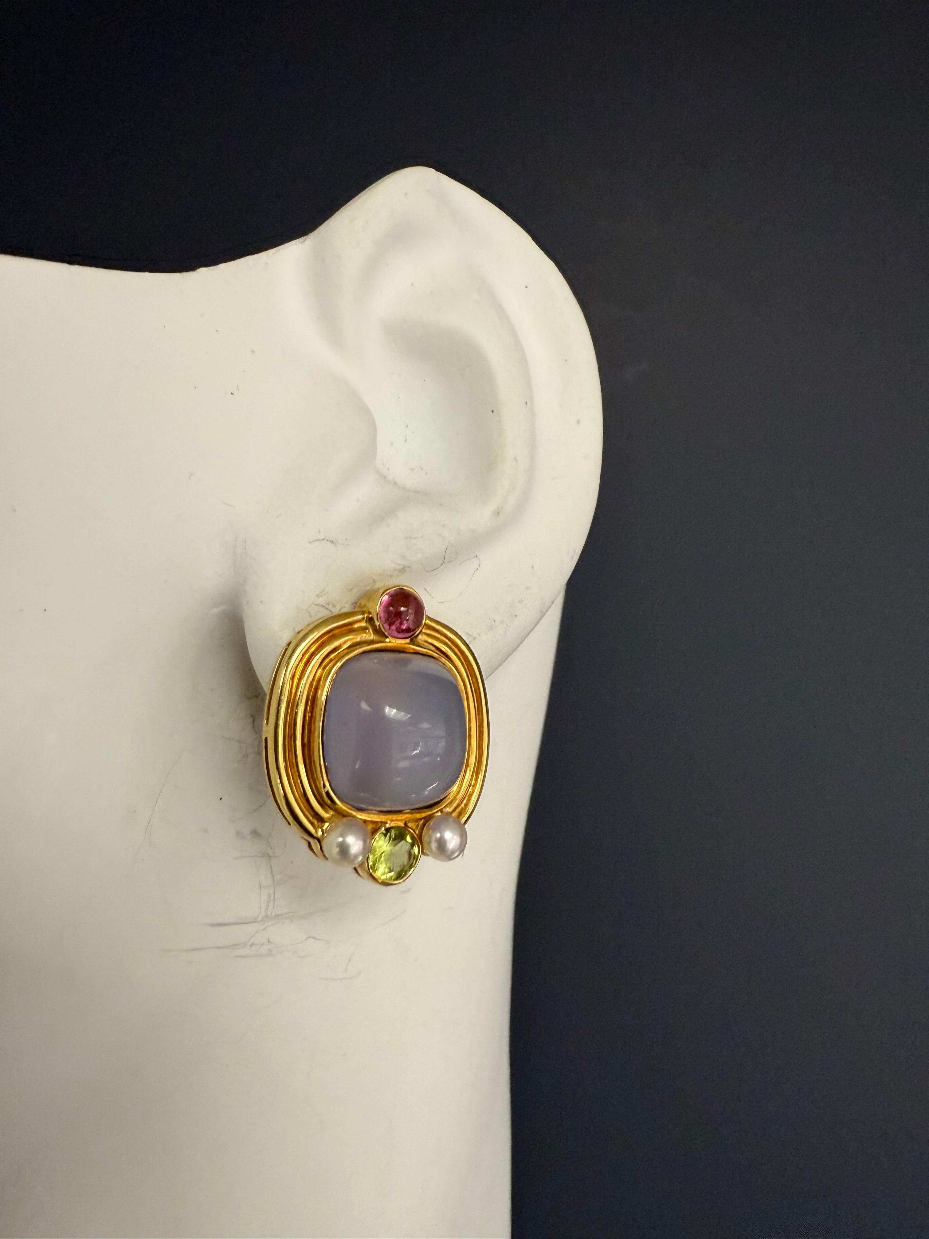 Orecchini retrò in oro giallo 18K con cabochon quadrati di calcedonio di circa 12 mm per 12 mm. Ogni orecchino presenta anche una tormalina cabochon, un peridoto verde incastonato e due piccole perle. Gli orecchini misurano 23 mm di lunghezza e 19