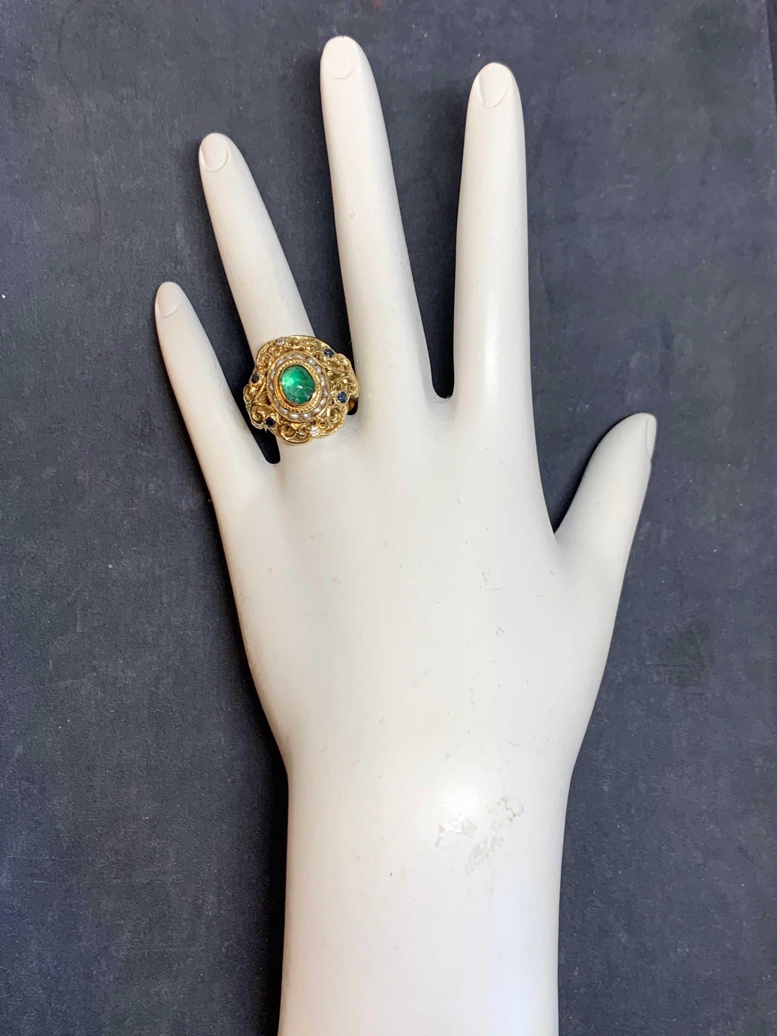 Retro 14k Yellow Gold Cocktail Ring set with approximately 2 carats including a Natural Emerald Cabochon, Sapphires, Diamonds & Pearls.

The center cabochon natural emerald measures approximately 7.8x5.5 and weighs approximately 1.50 carats.

The