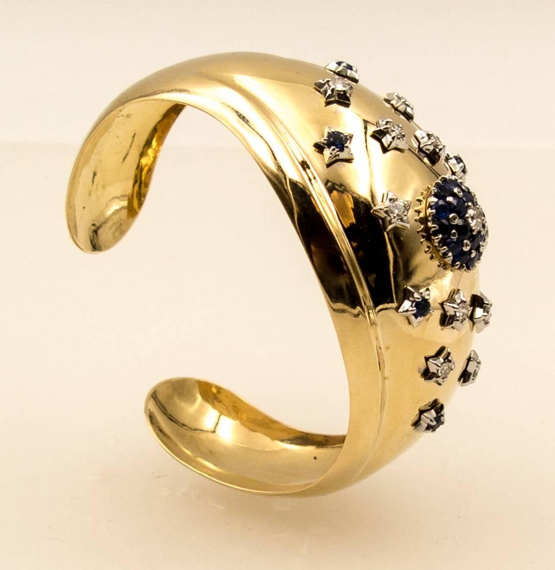 A strongly styled cuff bracelet from the 1940's : a domed center of highly polished yellow gold set with a central sapphire motif framed all around by diamonds set in white gold star designs.  Crafted in 14 karat yellow gold, made for the smaller