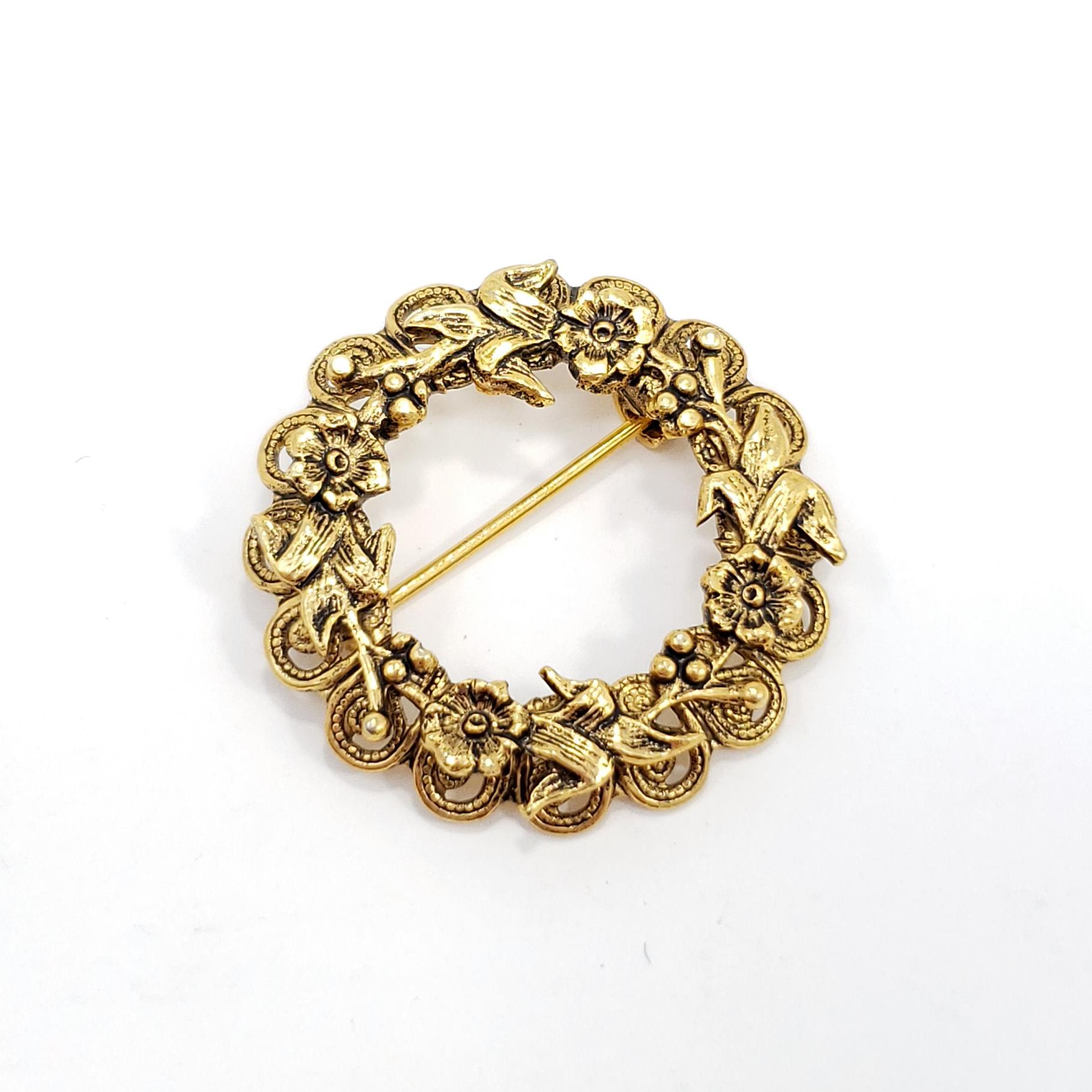 A stylish retro pin, featuring a wreath of ornate golden flowers. 

Gold-tone. Circa late 1970s..