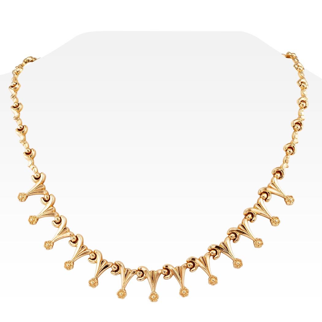 Retro gold fringe necklace circa 1950. Crafted in 18-karat gold as a series of elongated, interlocking links, decorated to the front with a complimentary fringe motif, each fringe terminating upon a single flower. We love the daintiness and