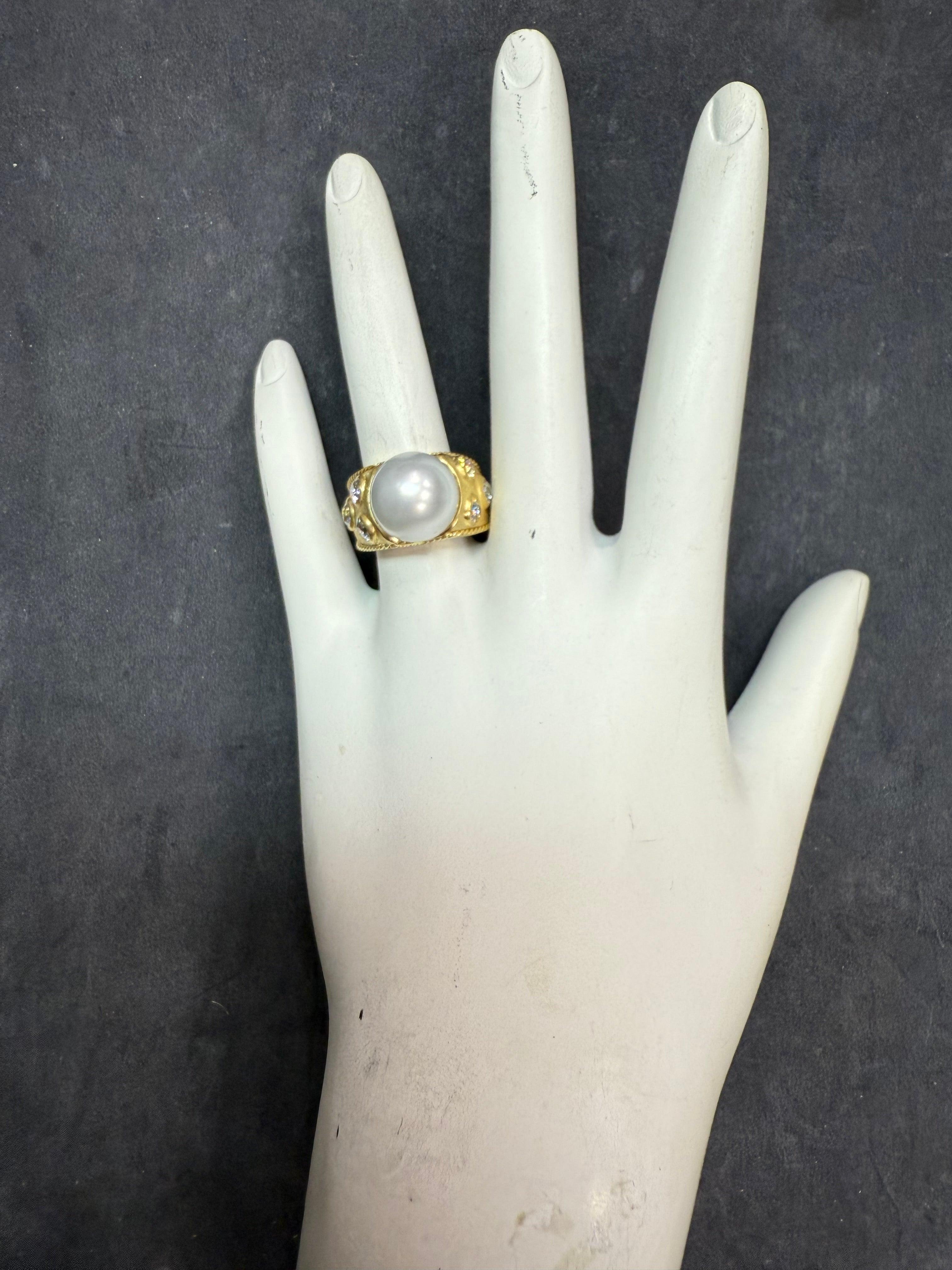 Retro 18K gold ring featuring a high-luster 11.5 mm natural South Sea pearl with thick nacre, accented by six natural old mine cut colorless diamonds totaling approximately 1.00 carat. 
The ring measures 11.5 mm at the top, tapering to 4.5 mm at the