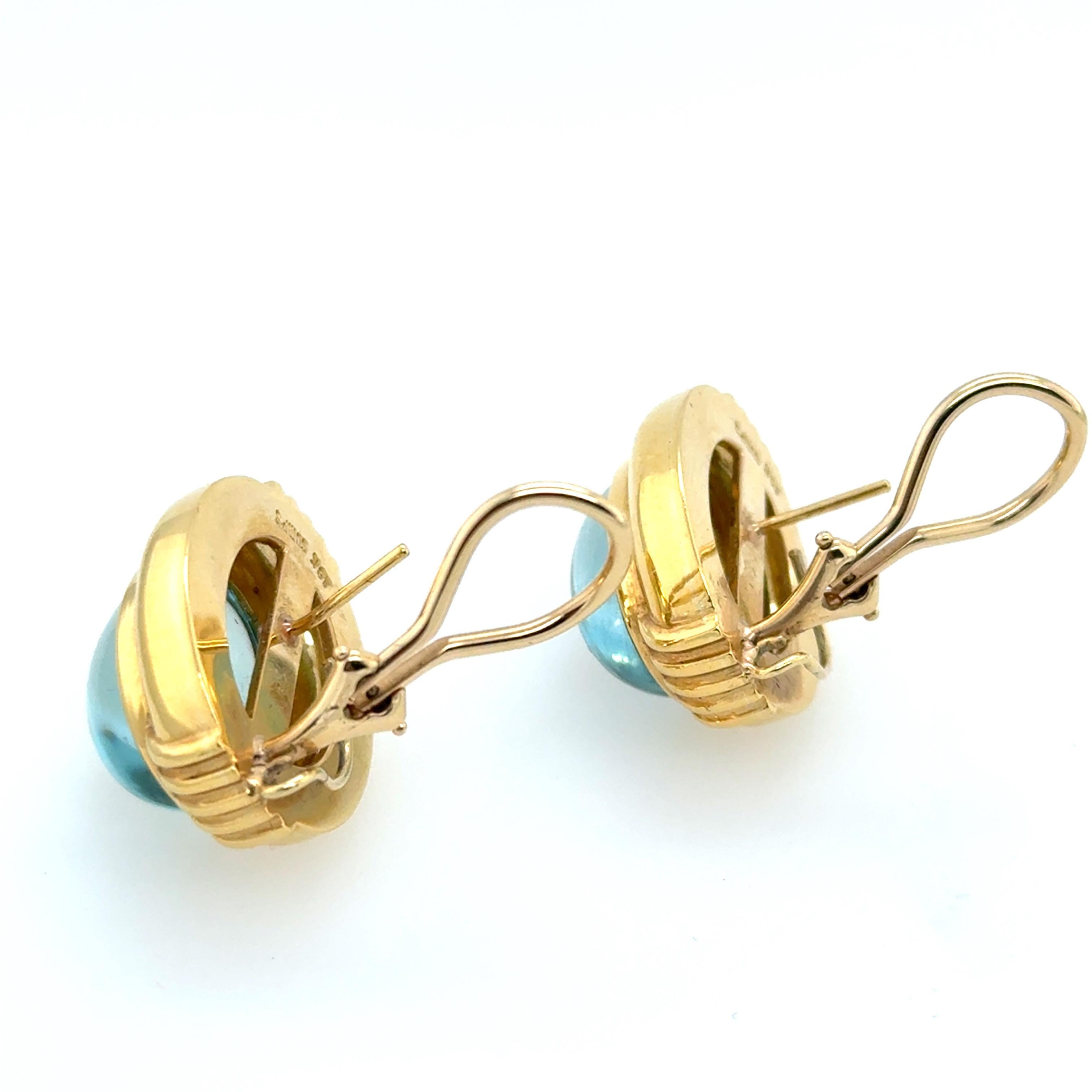 A magnificent pair of 18k yellow gold earrings by Gump’s, set with natural blue topaz cabochons measuring approximately 16mmx12mm. The earring mountings measure 23mmx18mm. Total weight is 22.3 grams.