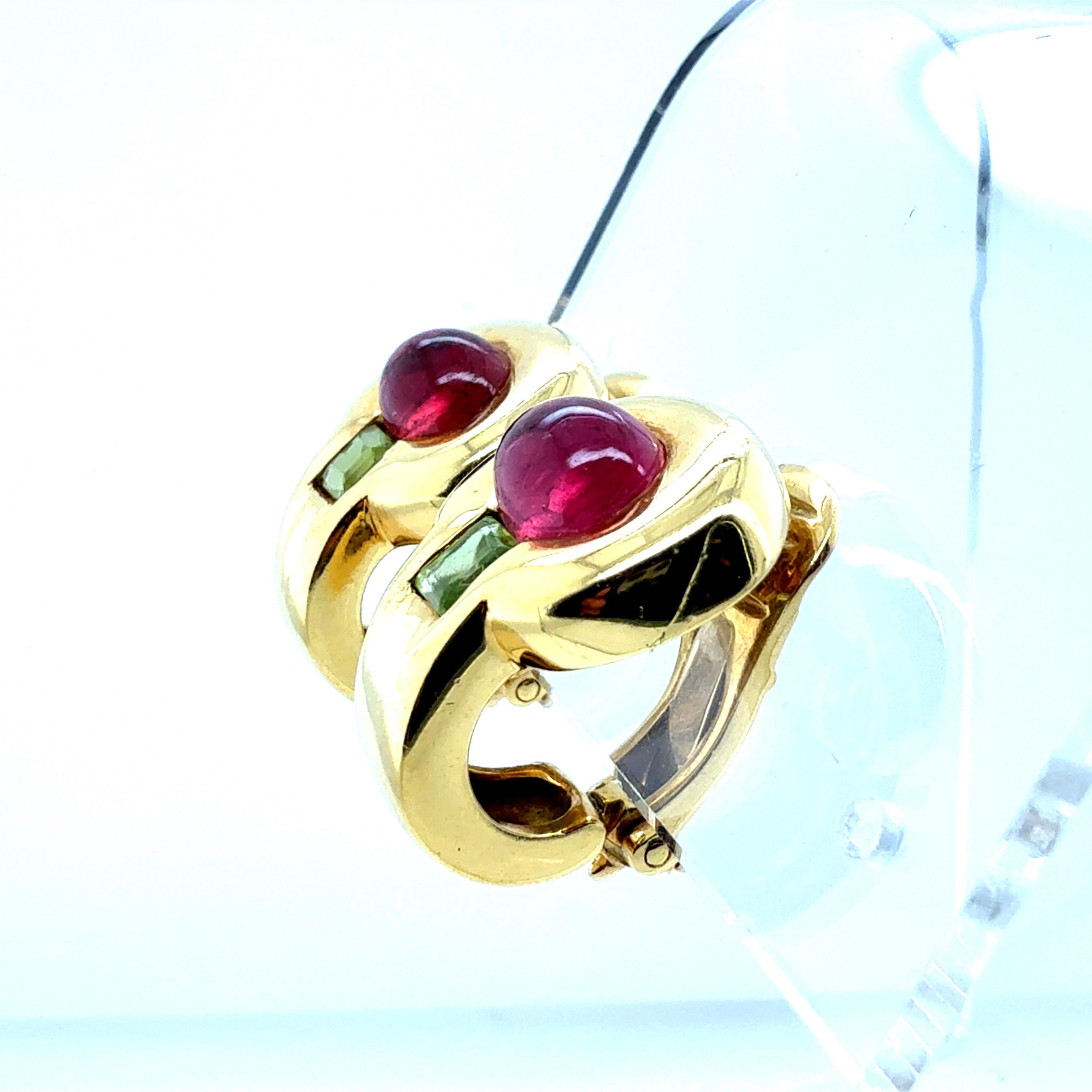 Boucles d'oreilles rétro à clip en or jaune 18 carats mettant en valeur deux cabochons de tourmaline naturelle éclatante. Les cabochons ovales mesurent environ 8,5 × 6,5 mm chacun et sont sertis pour mettre en valeur leur riche teinte. 

Les boucles