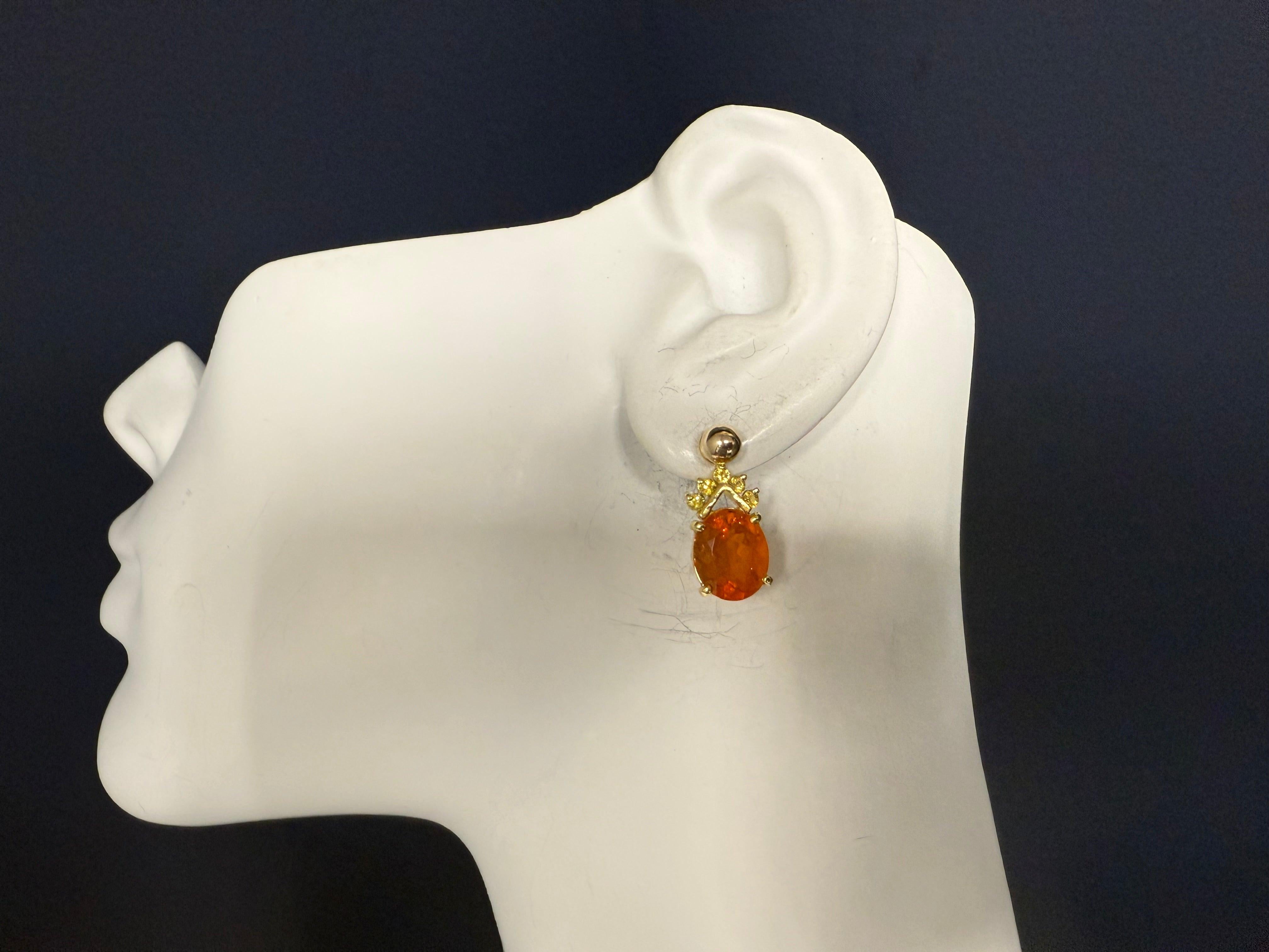 A pair of yellow gold earring enhancers featuring two stunning oval-shaped natural Mexican opals in vibrant orange, each measuring approximately 11 mm by 9 mm. Accented with five yellow gemstones, these enhancers measure a total of 21 mm in length