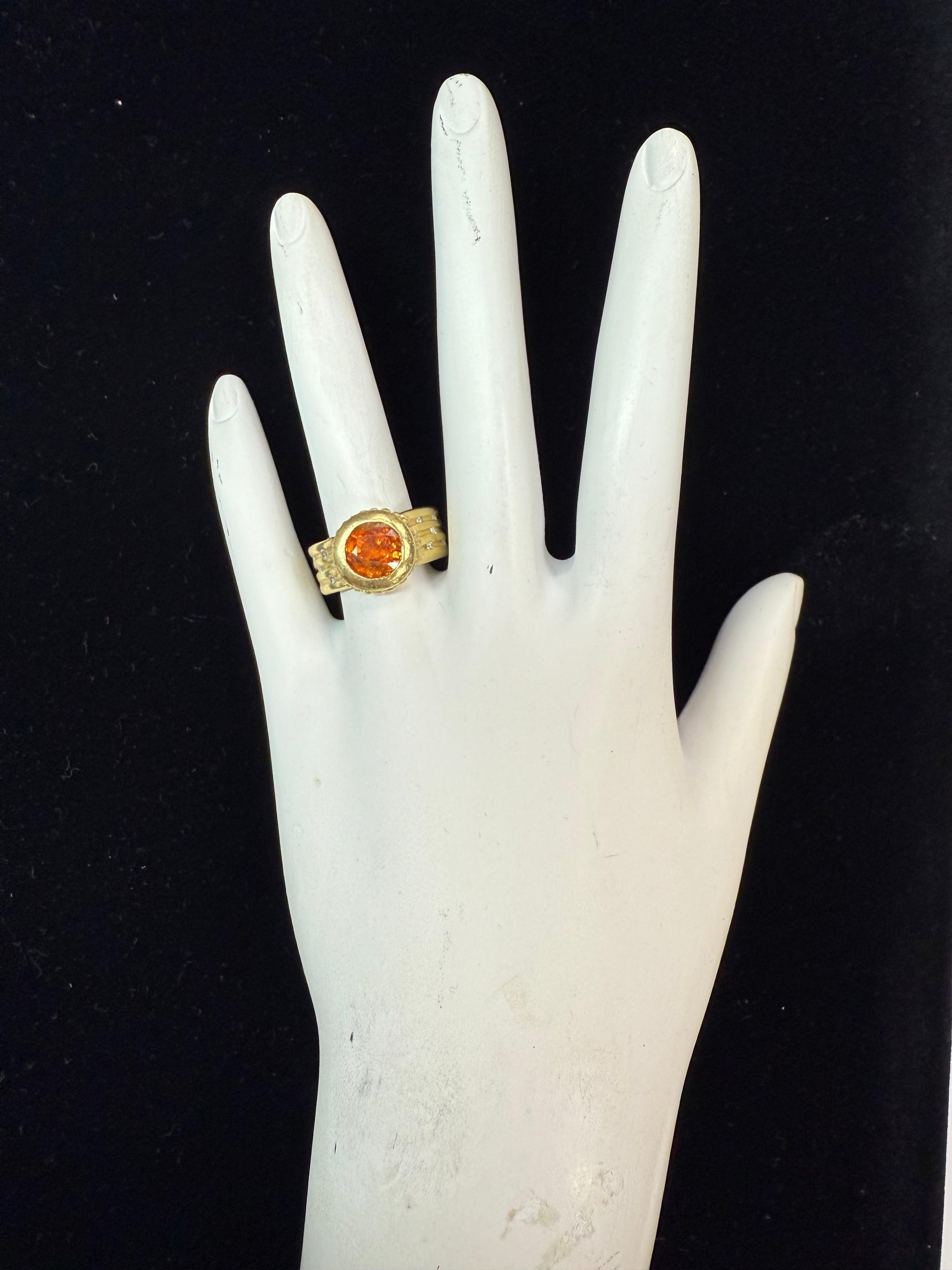 Bold and vibrant, this statement ring features an 8 mm wide spessartite garnet in a rich orange hue. Crafted in gold and weighing 10.6 grams, the ring is a size 6.25 and accented with 10 natural color diamonds for added brilliance and contrast. A