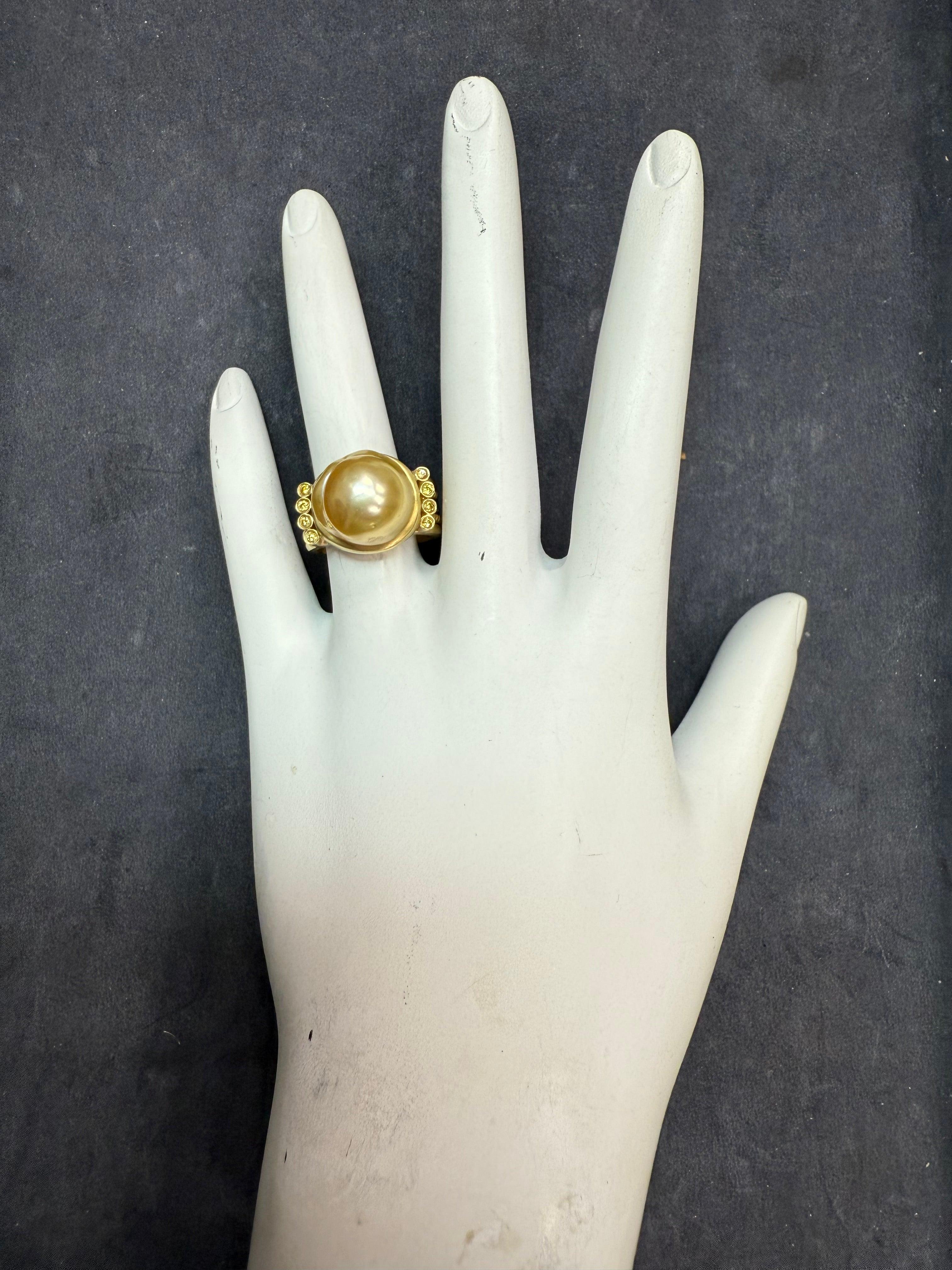 Retro 18K yellow gold statement ring showcasing a high-luster Golden South Sea pearl measuring approximately 12.5 mm in diameter and 9.5 mm in height, with thick nacre. 
The pearl is accented by eight round brilliant natural vivid yellow diamonds