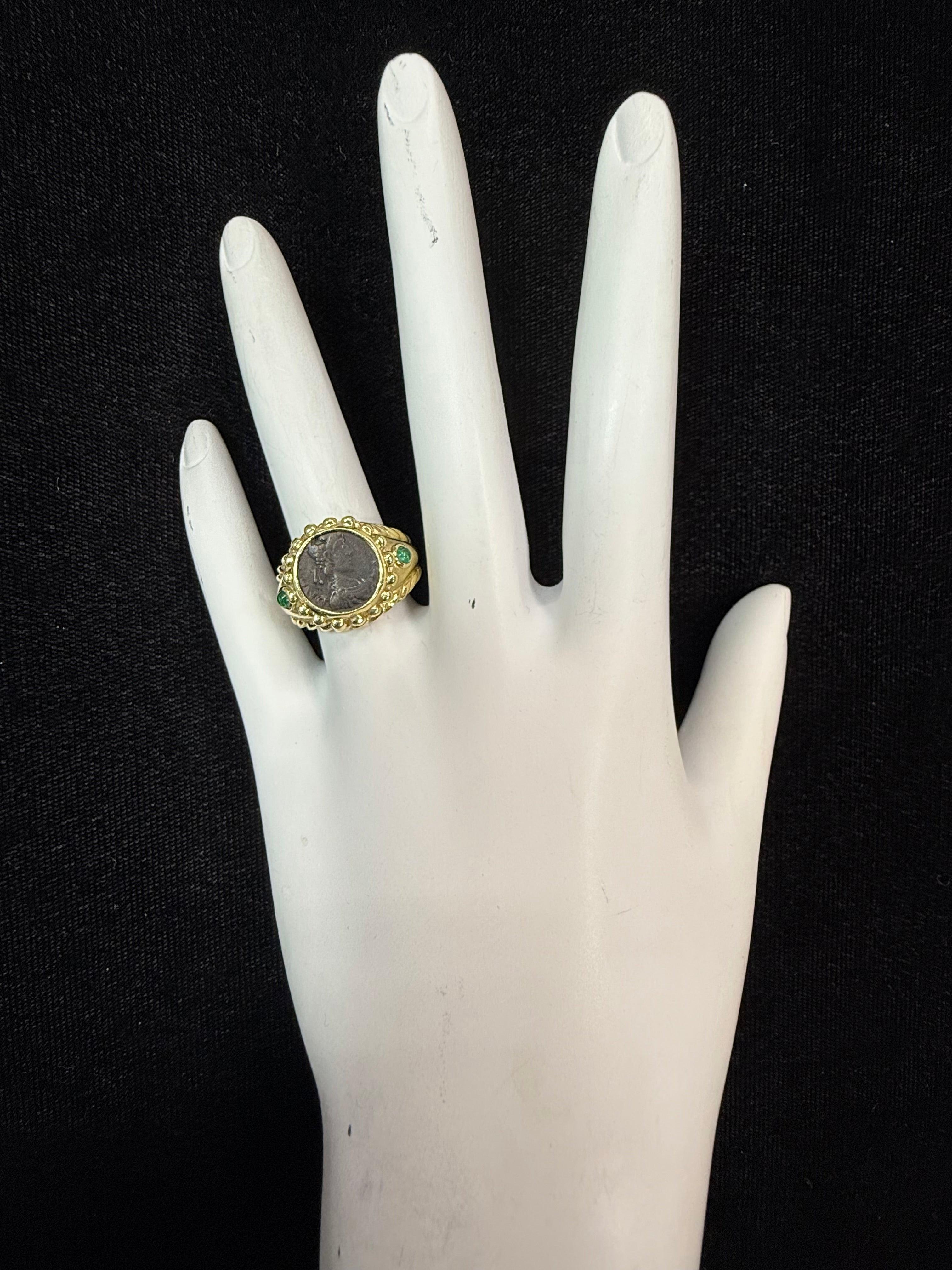 Bague rétro en or jaune 18 carats ornée d'une pièce de bronze antique représentant un empereur romain, sertie de deux émeraudes cabochon vertes naturelles. La bague pèse 9,6 grammes, est estampillée 750 et est de taille 5,5. Il mesure 14 mm de