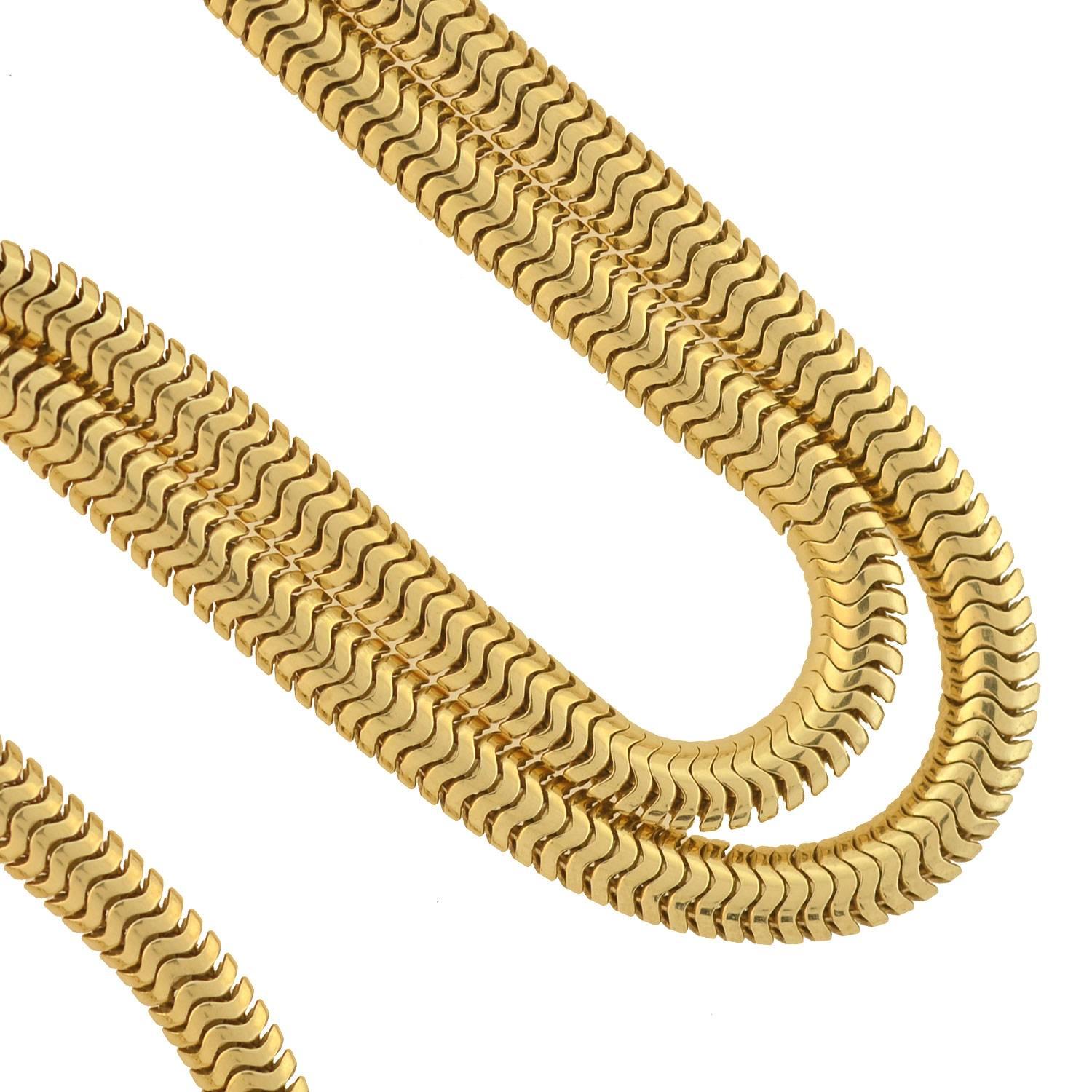 A very stylish chain necklace from the Retro (ca1940) era! This flexible snake chain has a sleek and simple design crafted in 14kt yellow gold. The chain has a fairly wide body and the subtle scaled design gives it the flexibility to curve along the